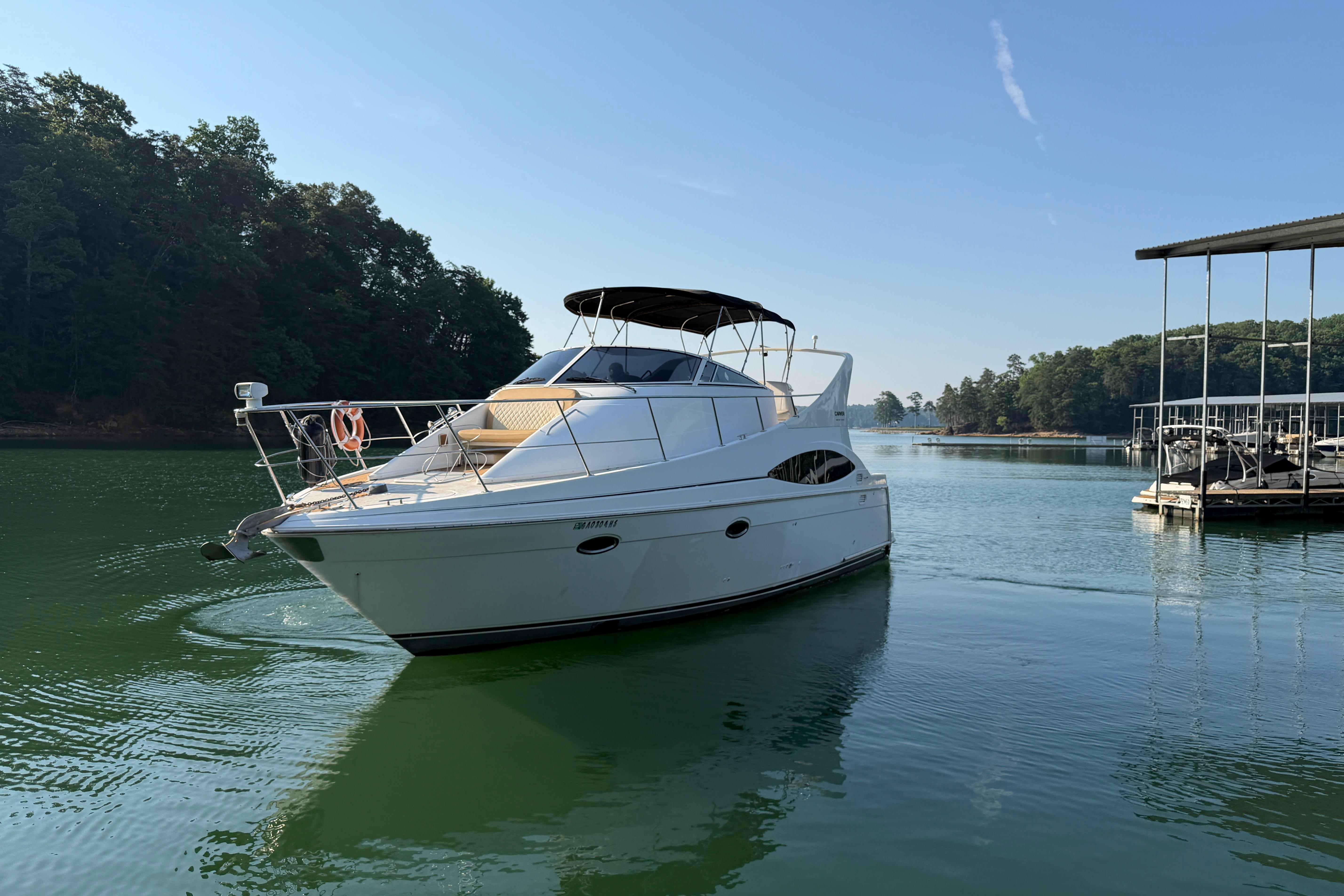 2003 Carver 350 Mariner yacht on a serene lake with lush green surroundings.