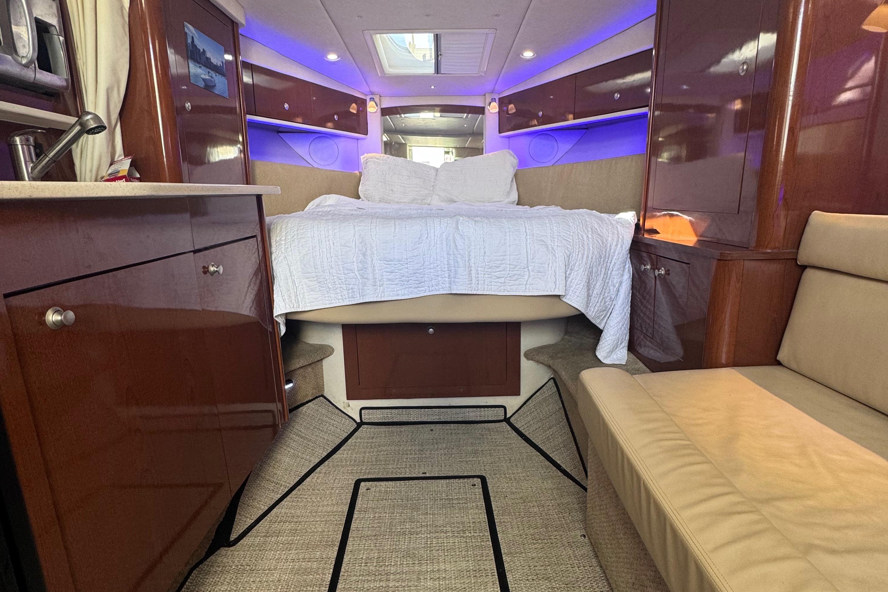 Luxurious interior of 2008 Sea Ray 350 Sundancer yacht with cozy bed and ambient lighting.