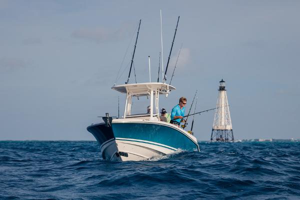 Manufacturer Provided Image: 2024 Boston Whaler 230 Outrage fishing boat on the ocean near a lighthouse.