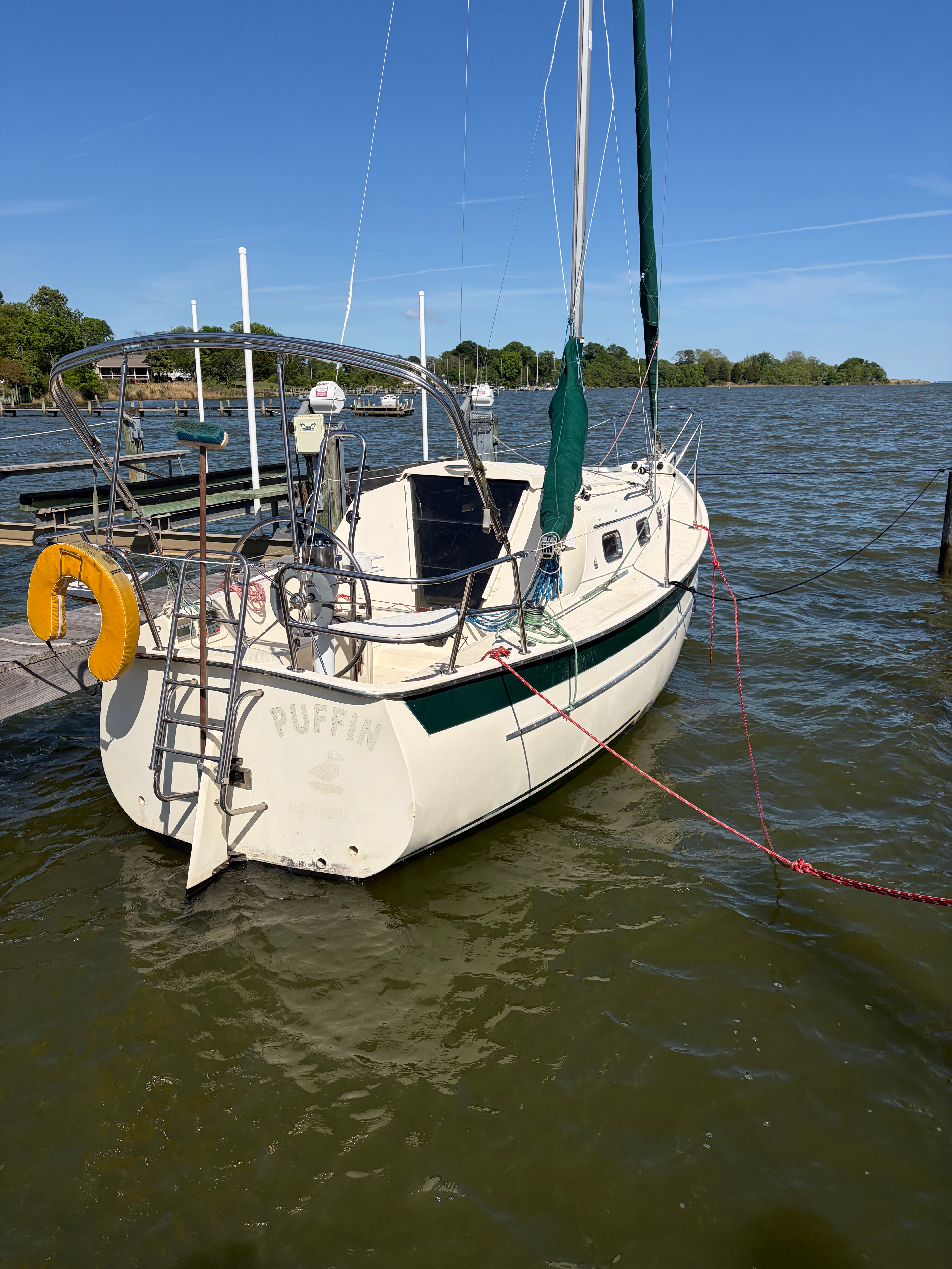 A sailboat docked at a pier, with a clear blue sky in the background.