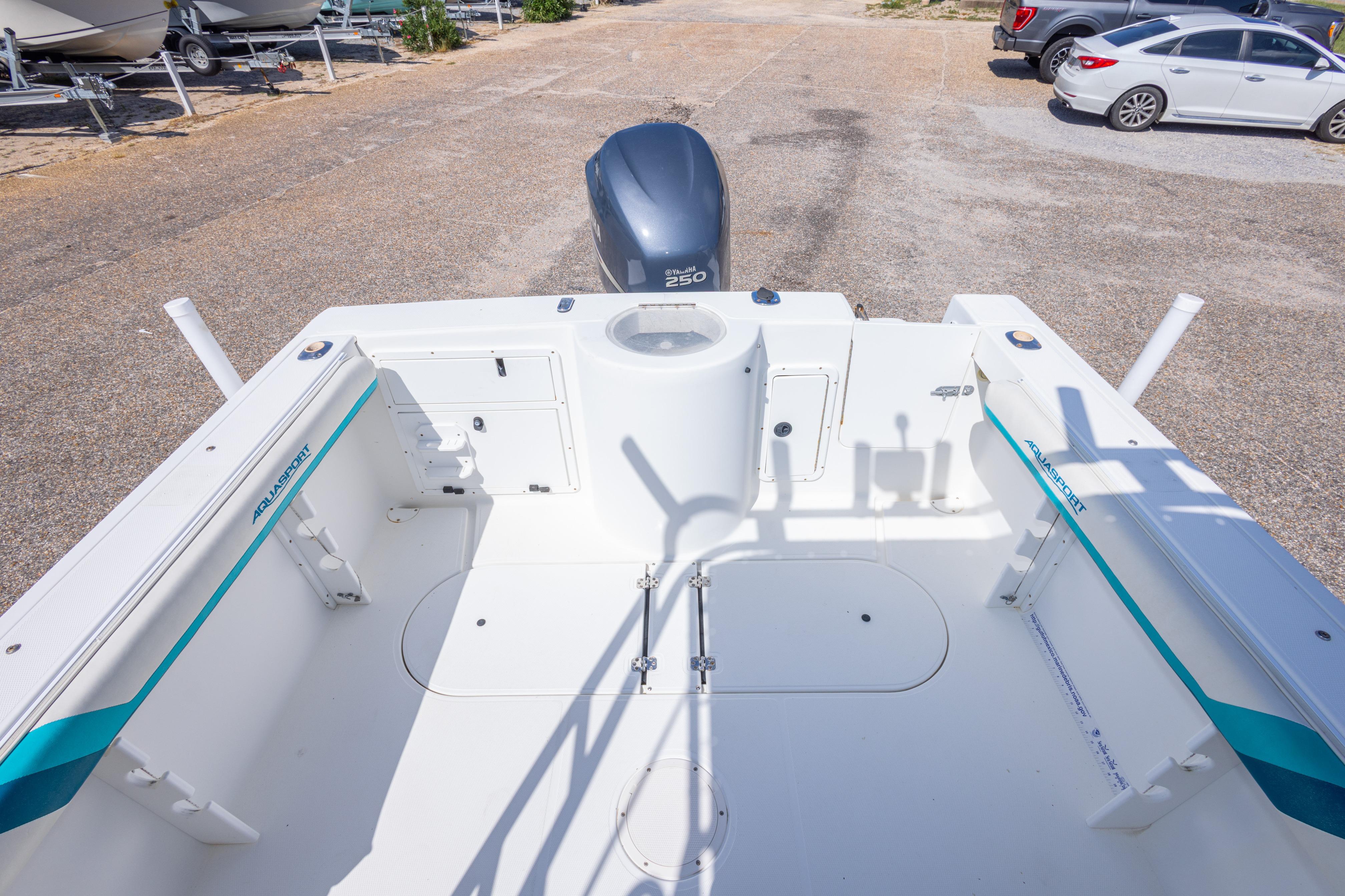 1999 Aquasport 225 Explorer boat interior with seating and storage, parked on a lot.