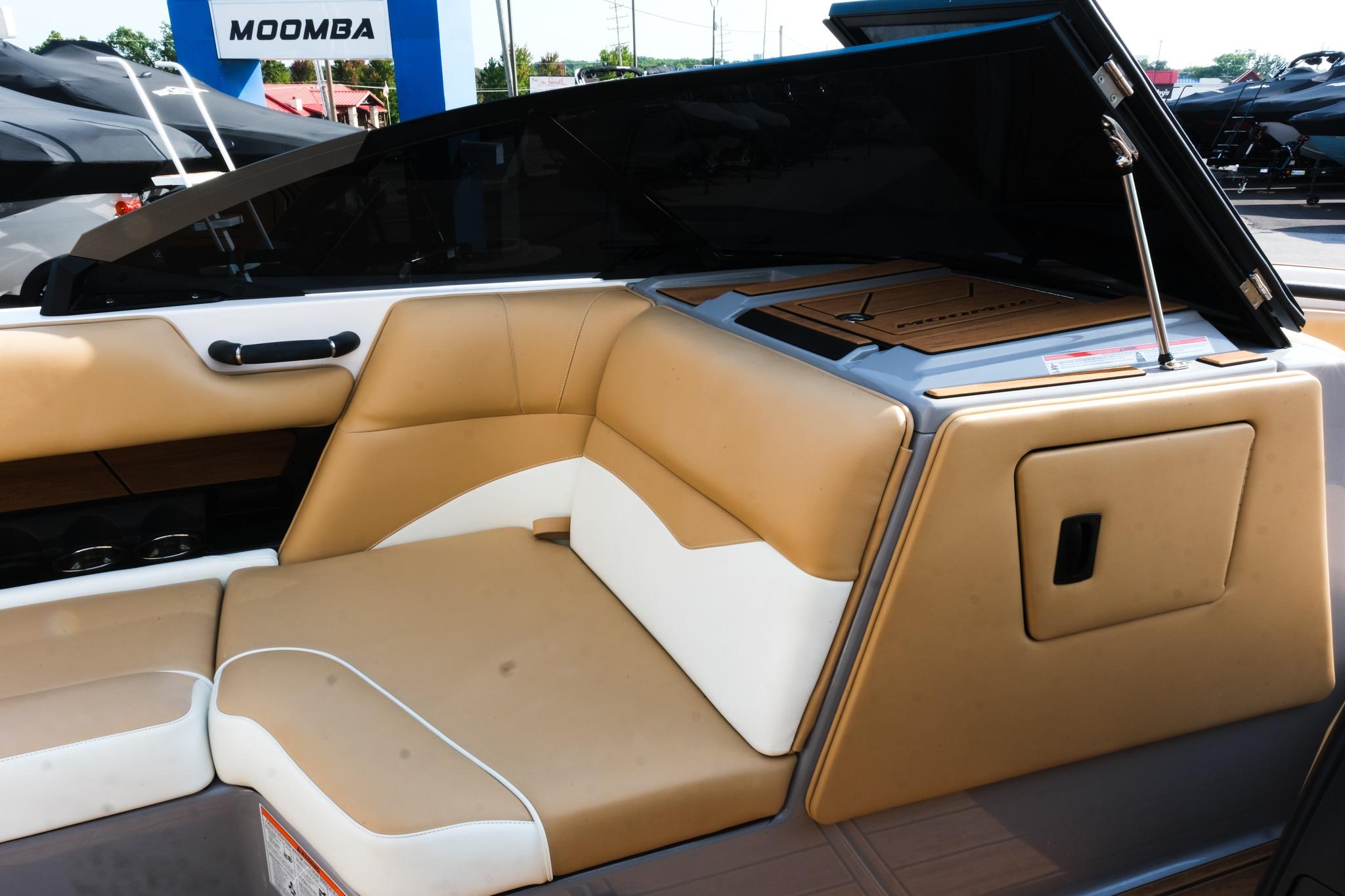 2023 Moomba Mondo boat interior with tan and white seating, open storage compartment.