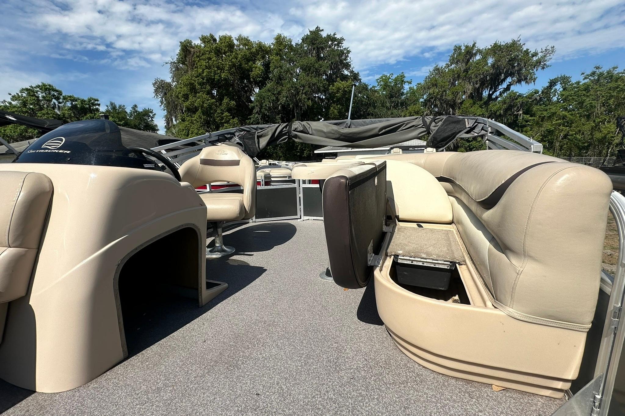 2016 SUNTRACKER Party Barge 20 interior with beige seating and helm, under blue sky.