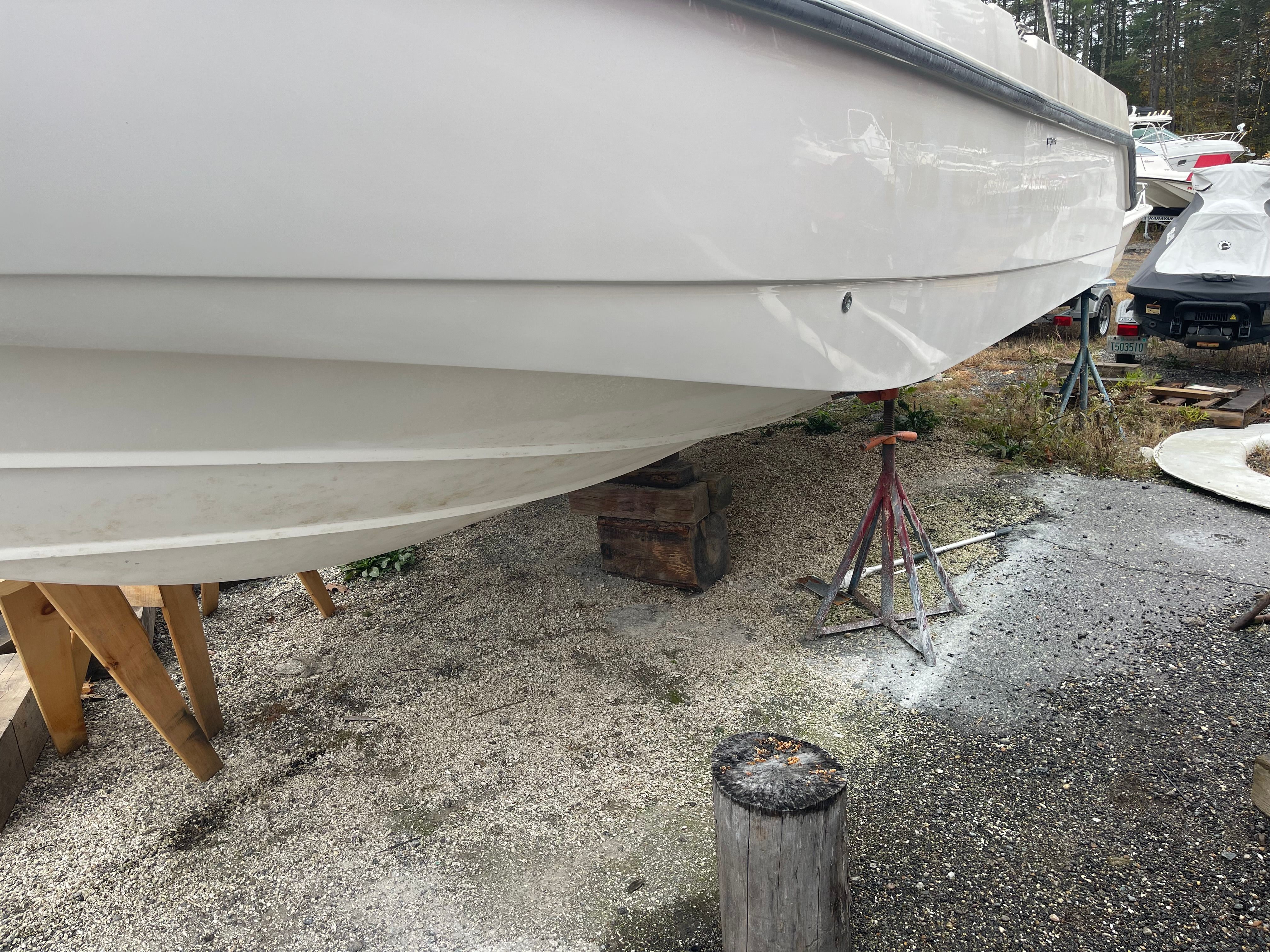 Boston Whaler 26 Conquest 2001 propped on gravel ground.