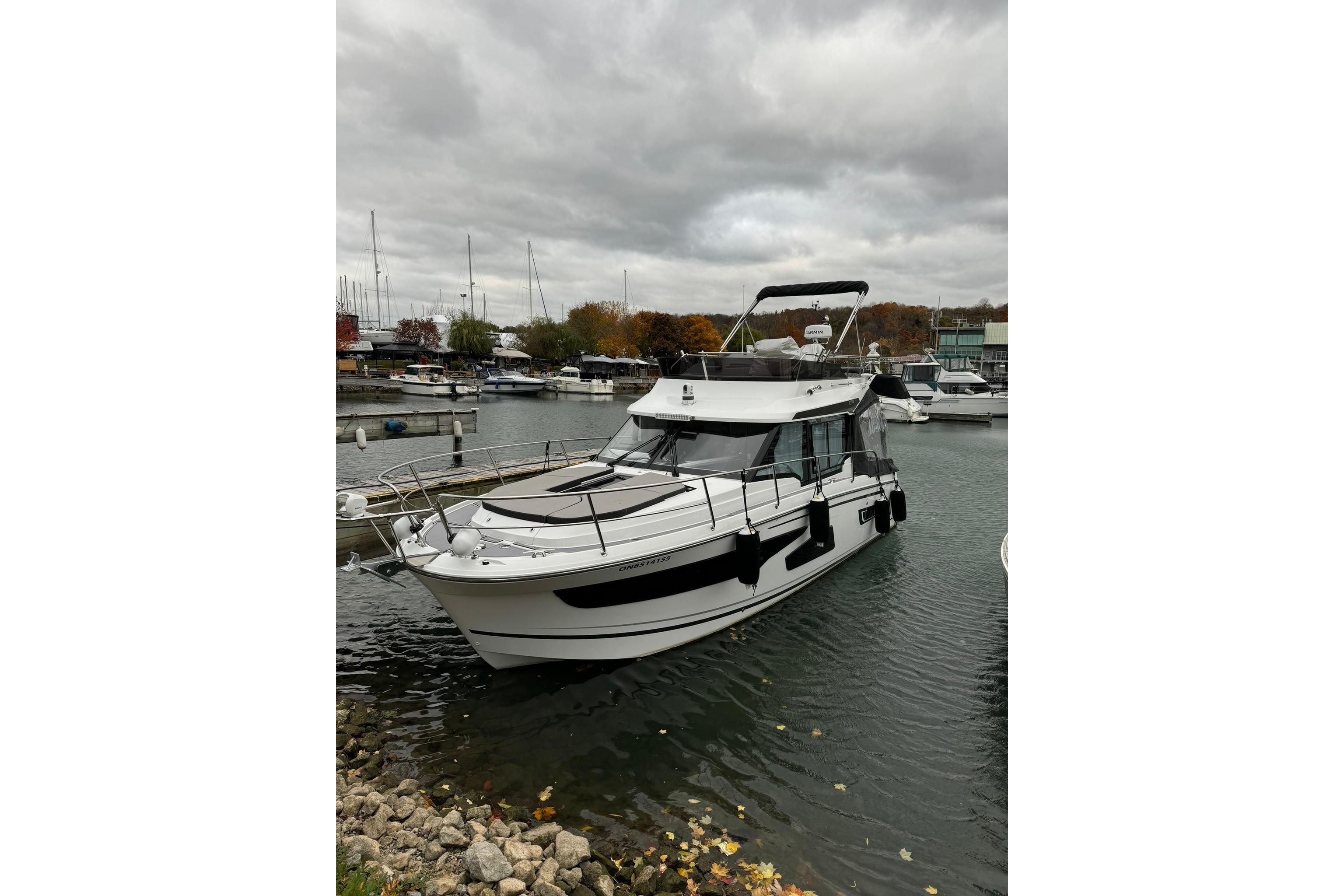 2022 Jeanneau NC 1095 Fly yacht docked in a marina under cloudy skies.