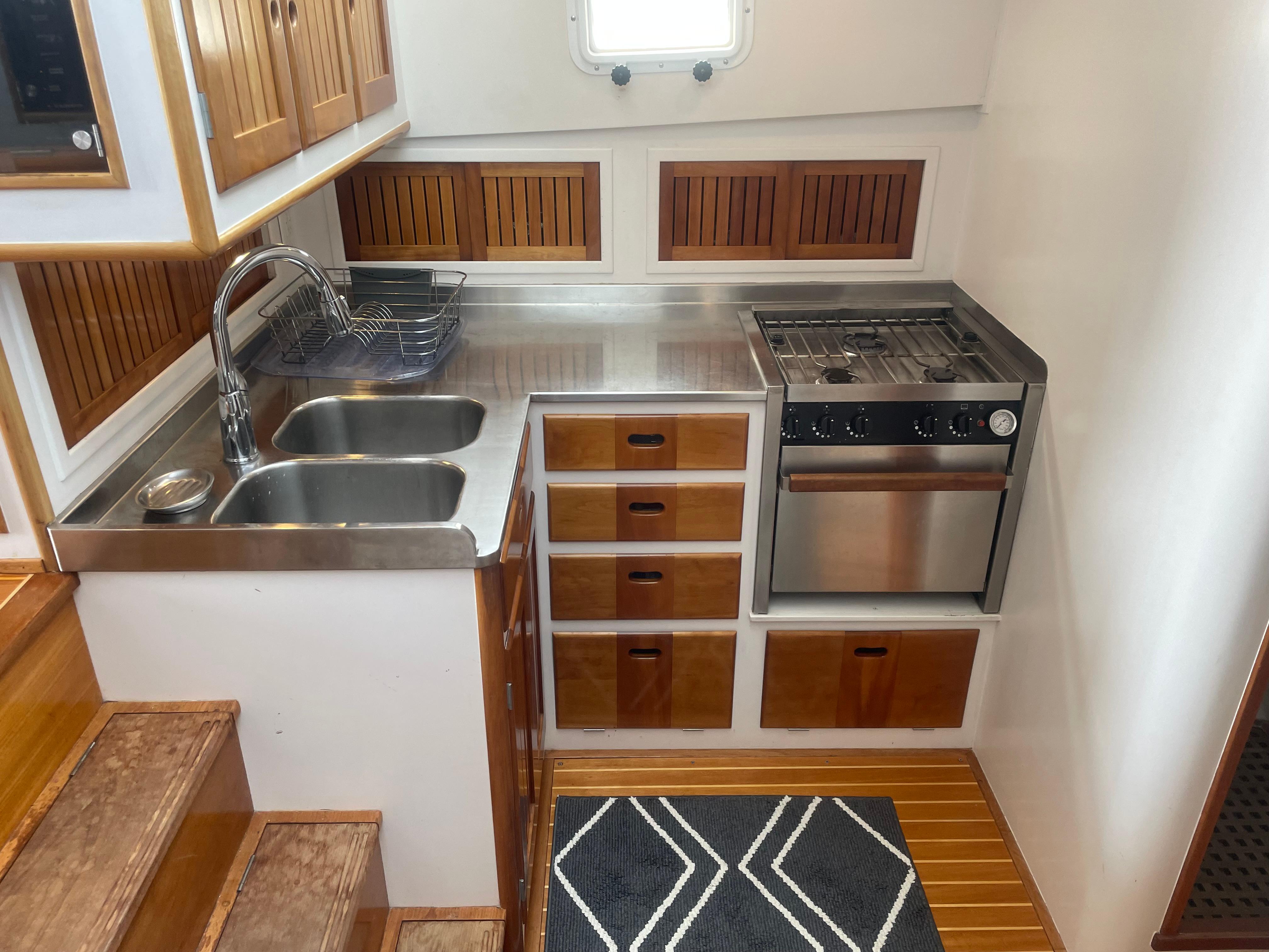 1997 Lyman-Morse Custom Flybridge kitchen with stainless steel sink, stove, and wooden cabinetry.