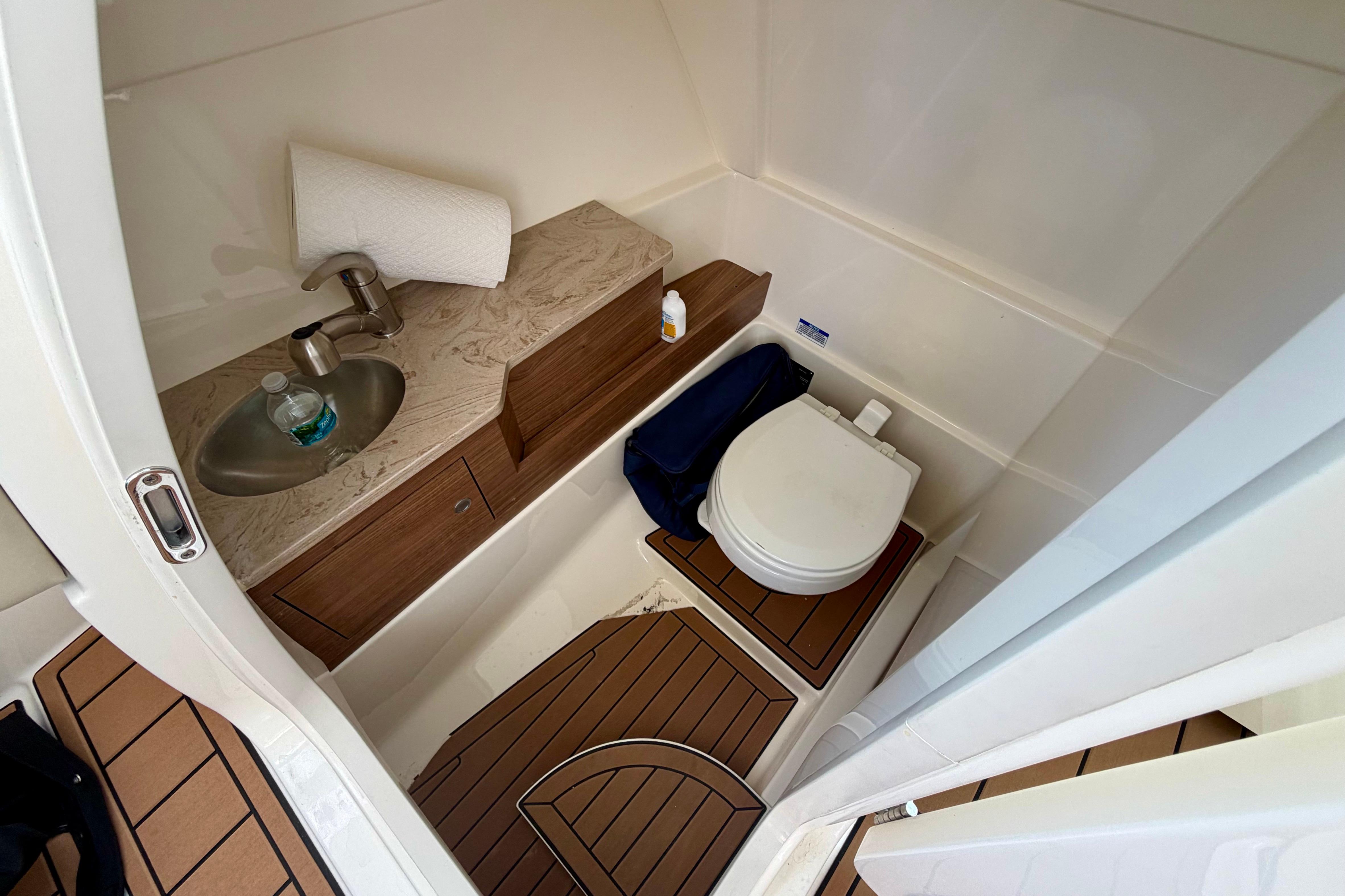 2022 Boston Whaler 280 Vantage boat bathroom with sink, toilet, and wooden flooring.