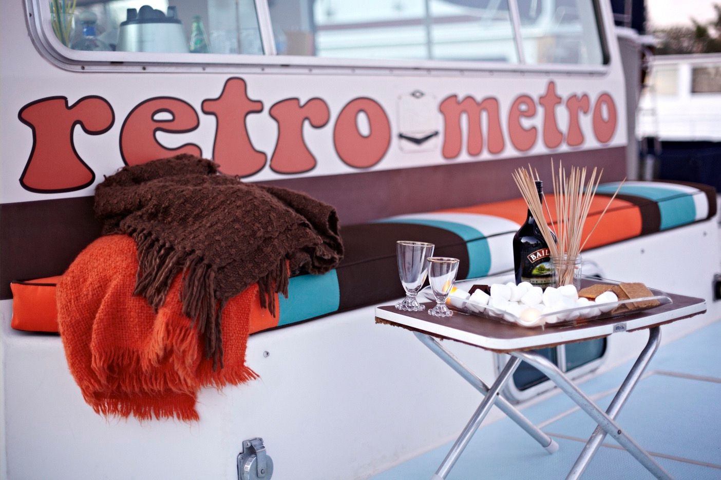 A cozy area on a houseboat with blankets and snacks on a table.