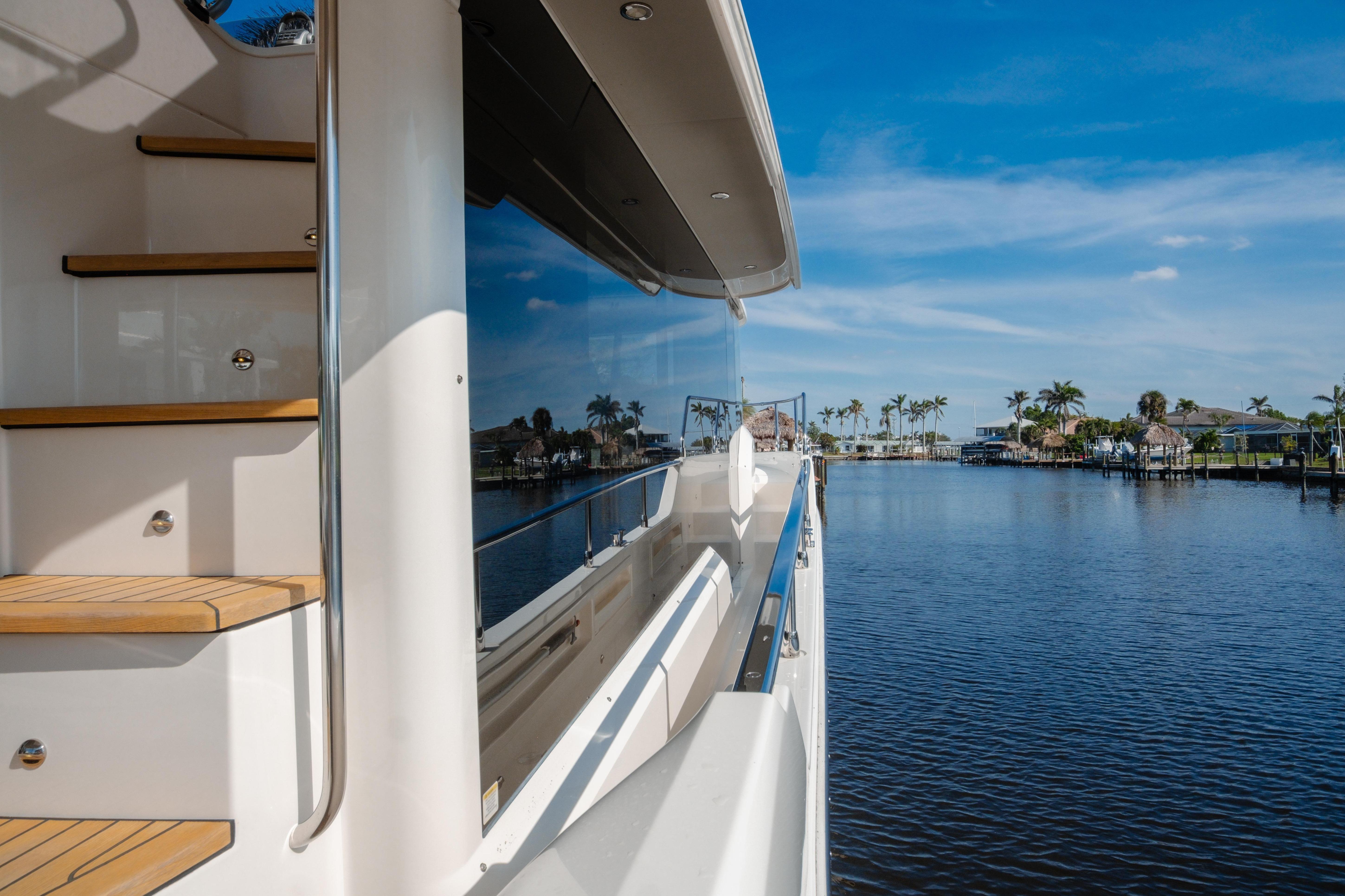 Absolute 48 Navetta 2020 yacht on serene waterway with clear blue sky.
