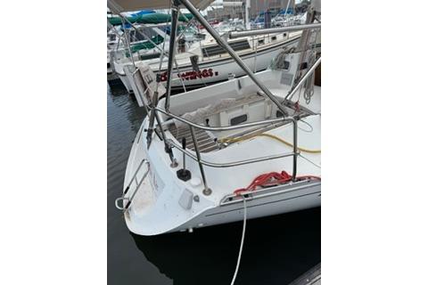 1986 Beneteau First 305 sailboat docked in a marina, featuring a clean white deck.