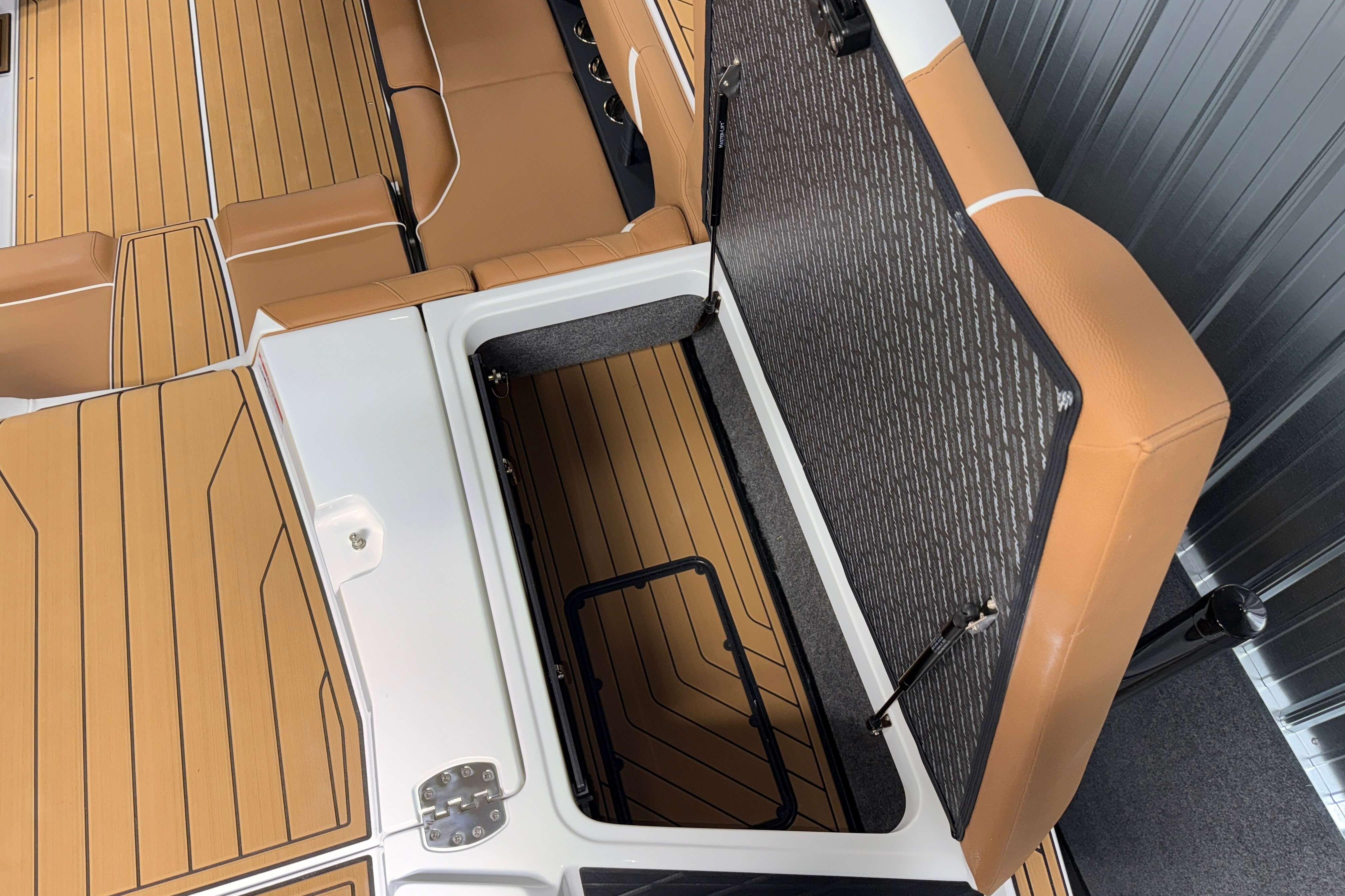 2026 Nautique Super Air Nautique S23 interior with open storage compartment and tan seating.