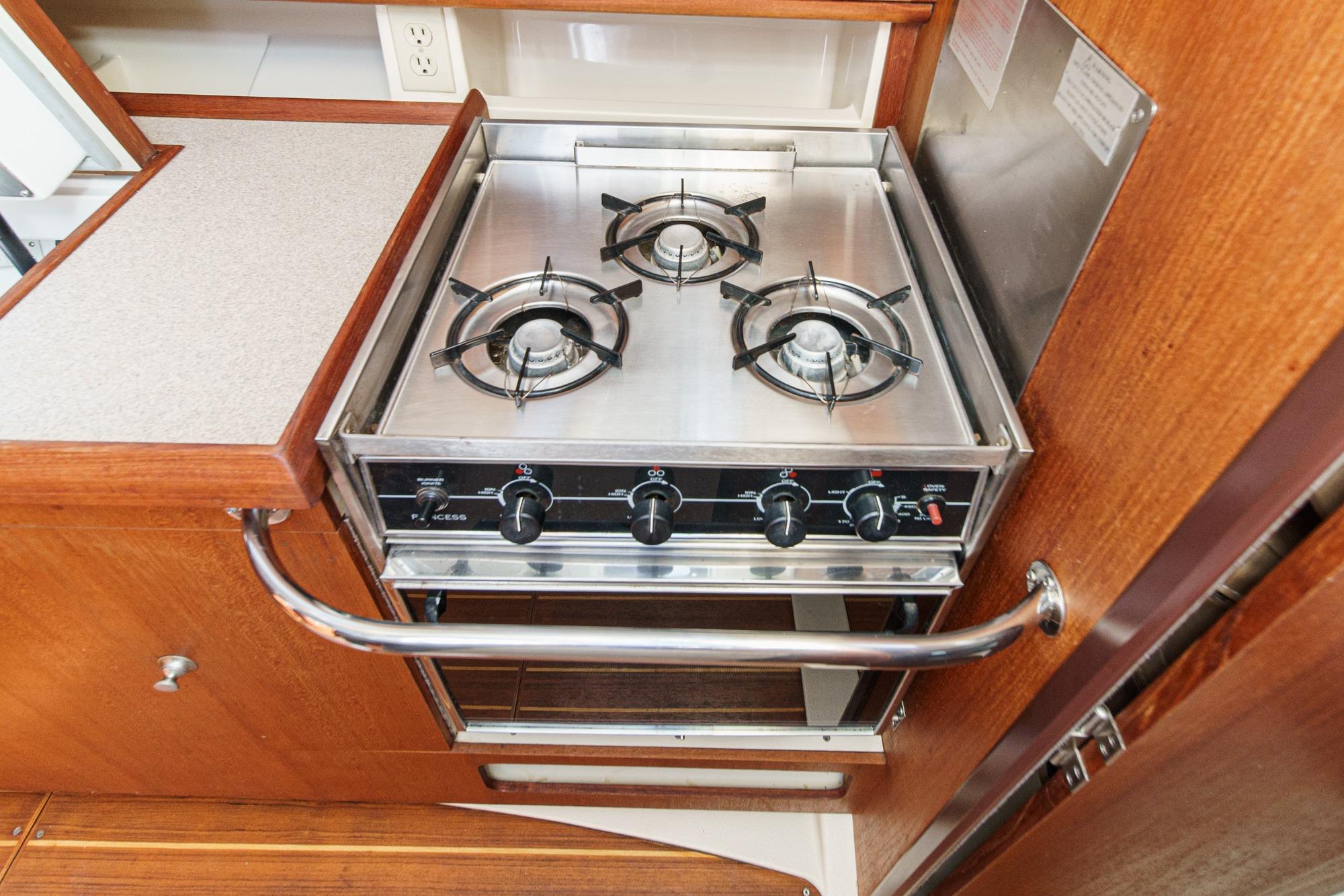 Three-burner stove in 1996 Hunter 376 yacht kitchen, featuring stainless steel and wood finish.