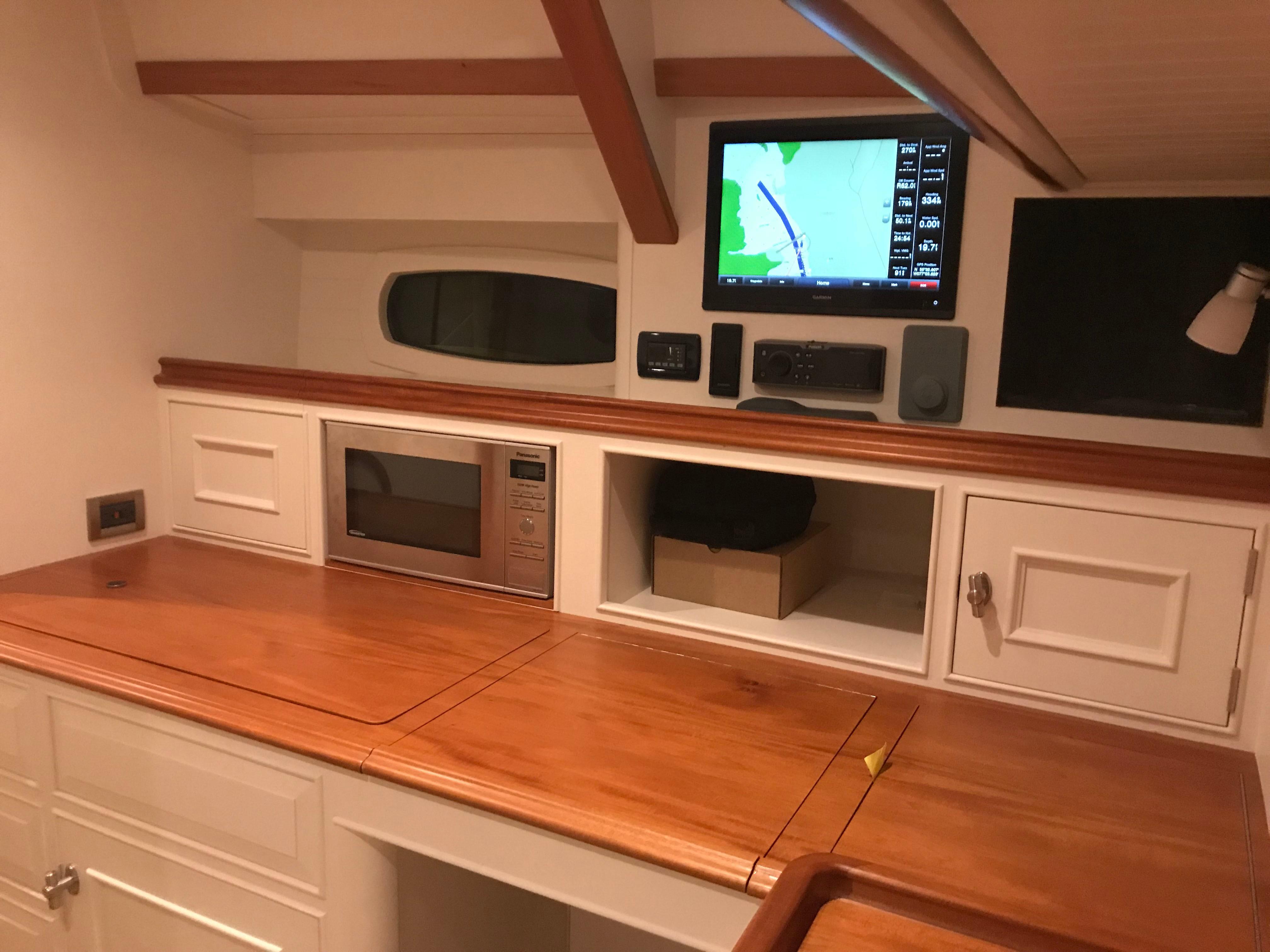 Interior of 2025 Surfari 50 yacht with wooden countertop, microwave, and navigation screen.