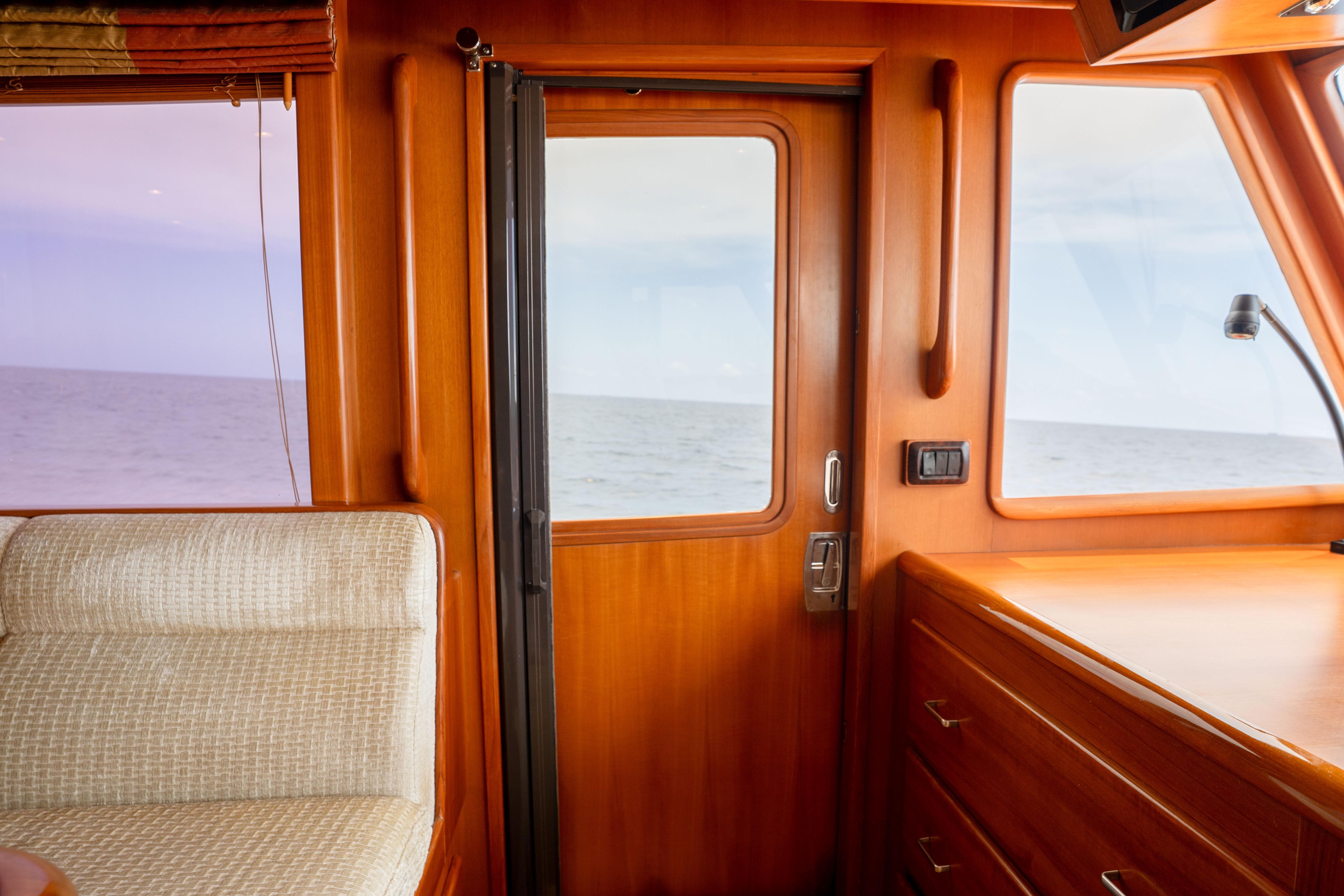 Interior of 2006 Fleming 75 yacht with ocean view through wooden cabin door.