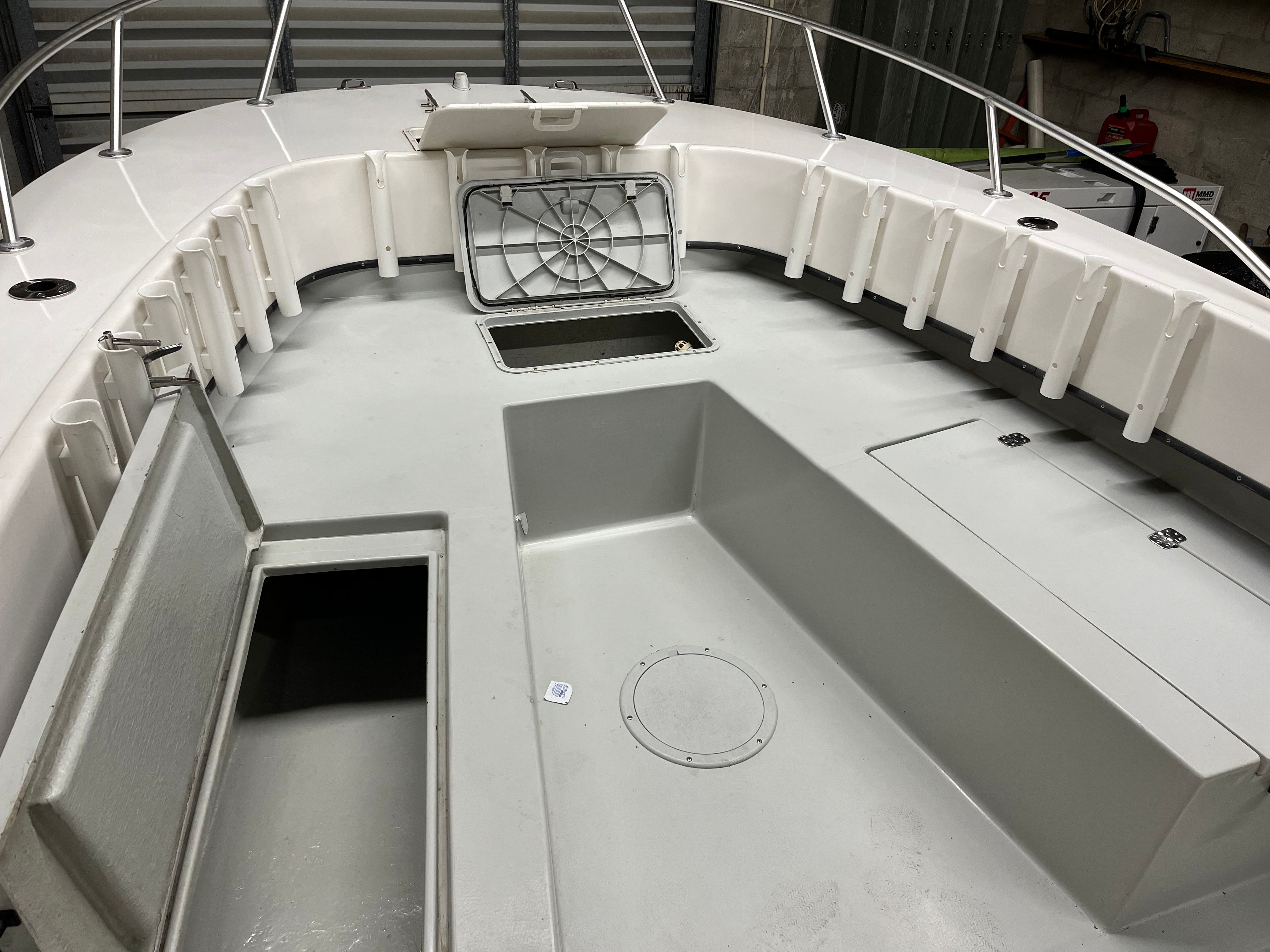 The image shows a boat deck with storage compartments and fishing rod holders.
