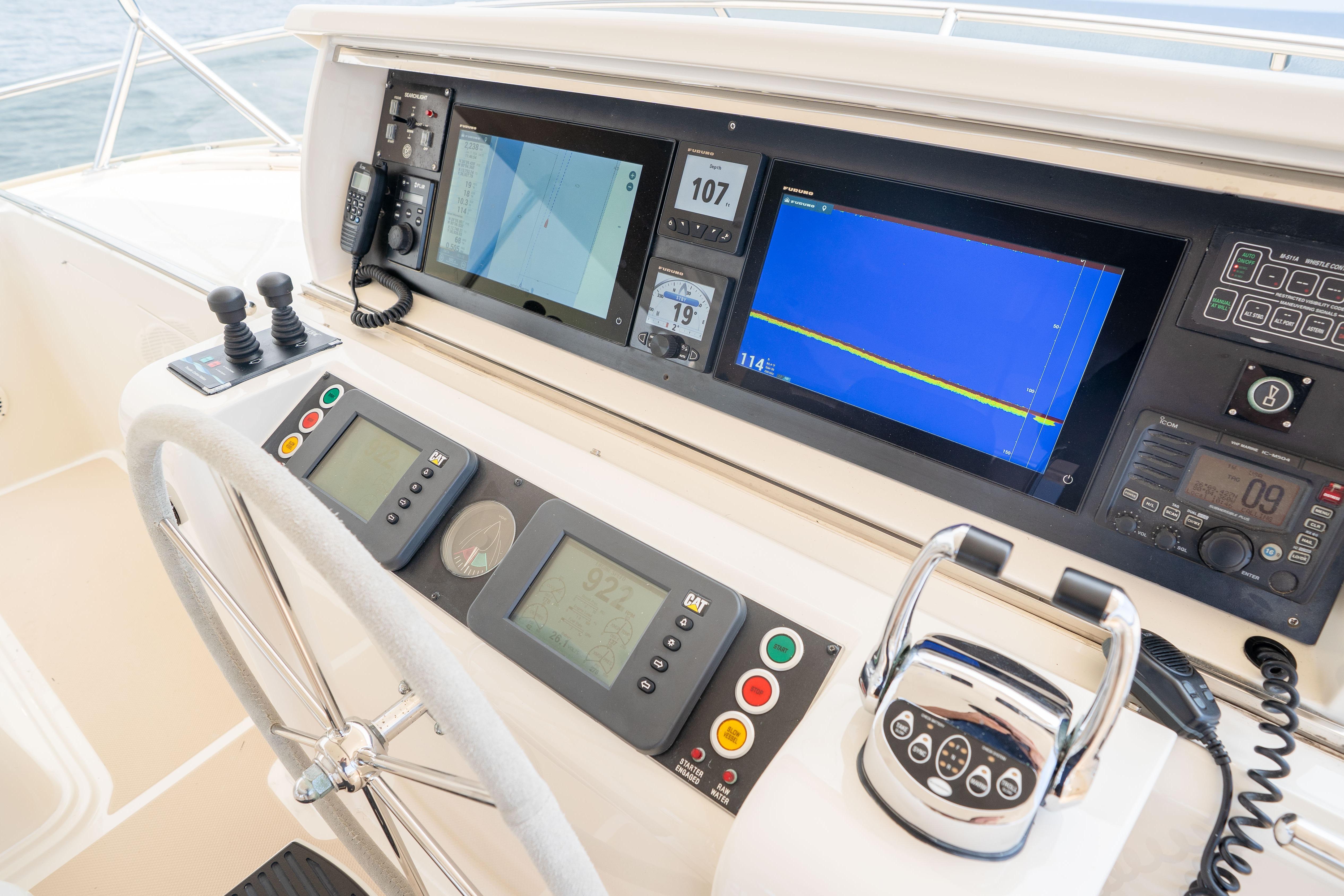 Control panel of a 2006 Fleming 75 yacht with navigation screens and steering wheel.