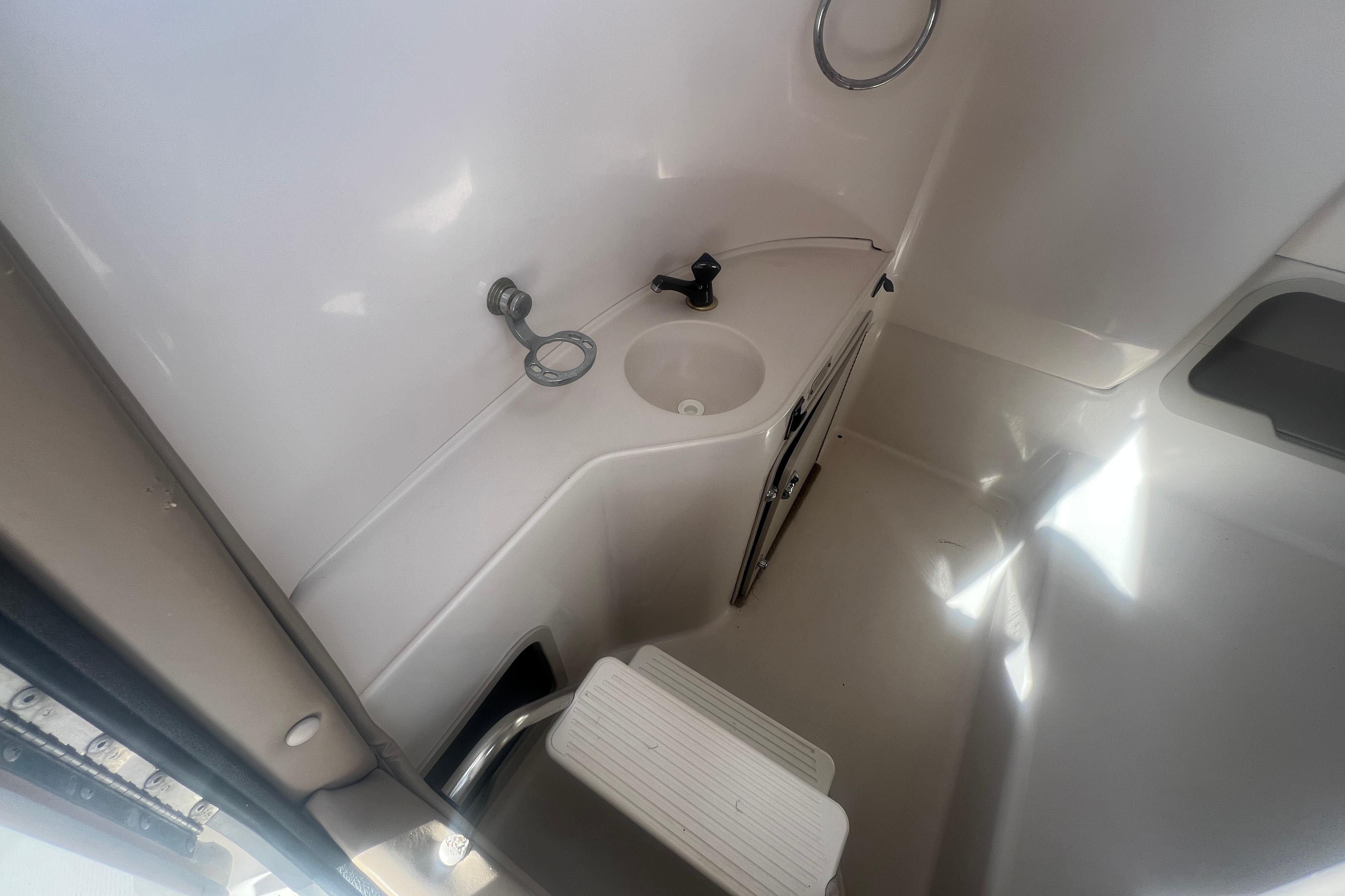 Interior of a 2002 Hurricane SunDeck 260 OB boat, featuring a compact sink and step.