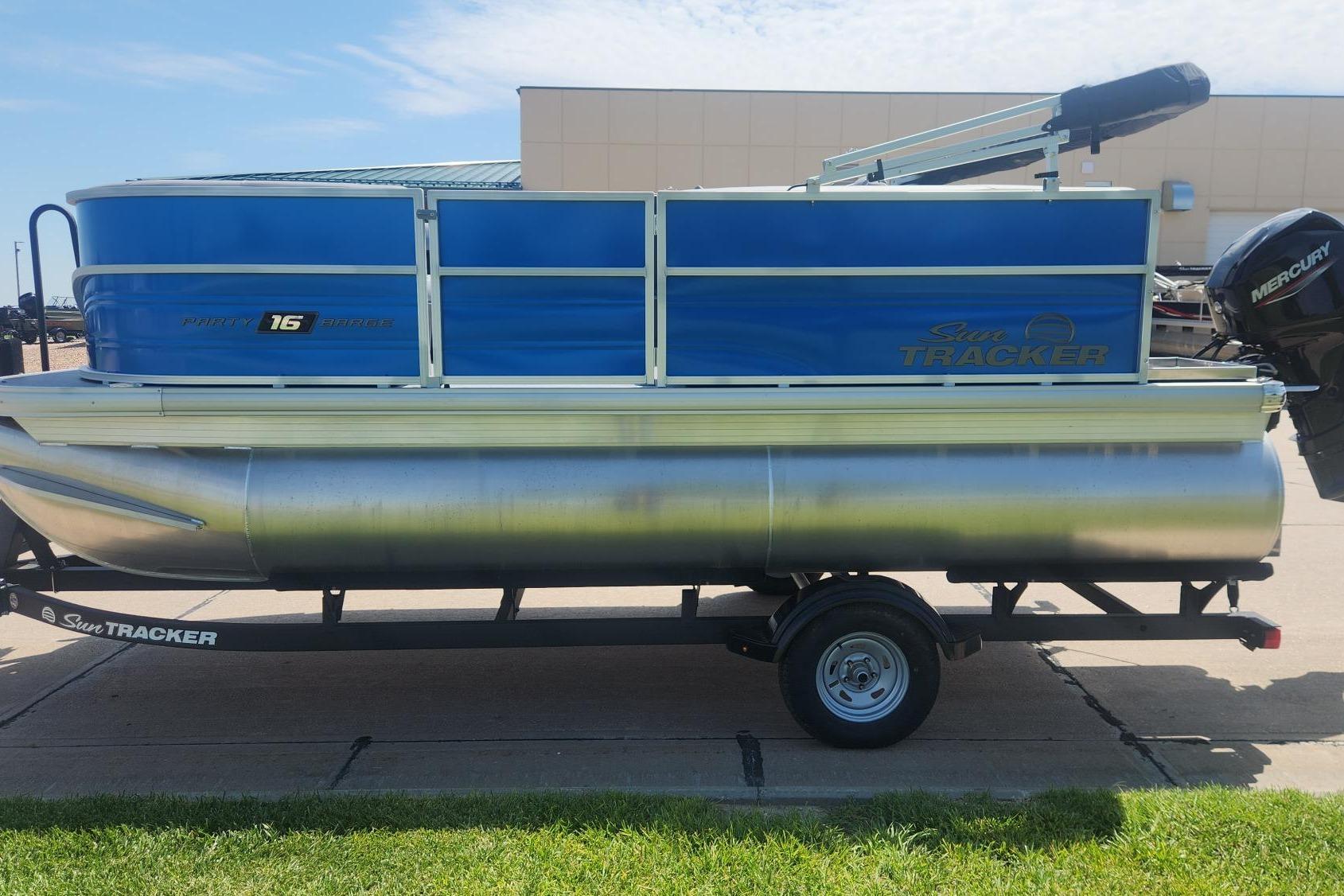 2026 Sun Tracker Party Barge 16 DLX pontoon boat on trailer, blue and silver design.