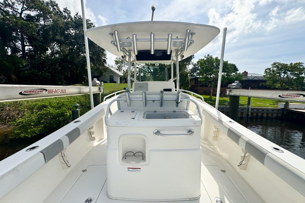 2018 Mako 284 Center Console boat docked near lush greenery.