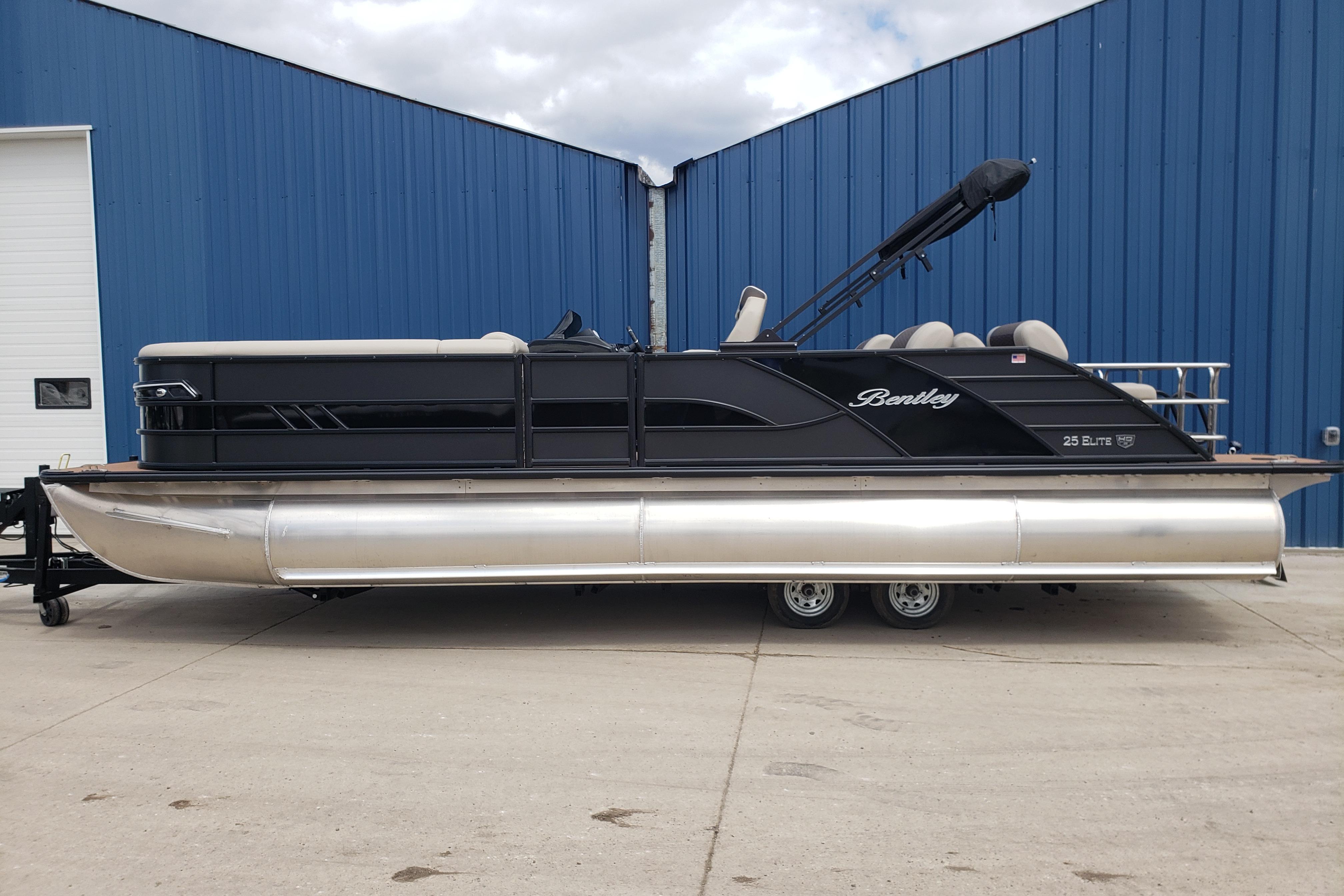2026 Bentley Pontoons Elite 253 QSB pontoon boat, black exterior, parked by blue building.