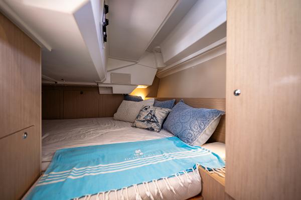 Interior of Beneteau Oceanis 38.1, cozy cabin with bed and pillows.