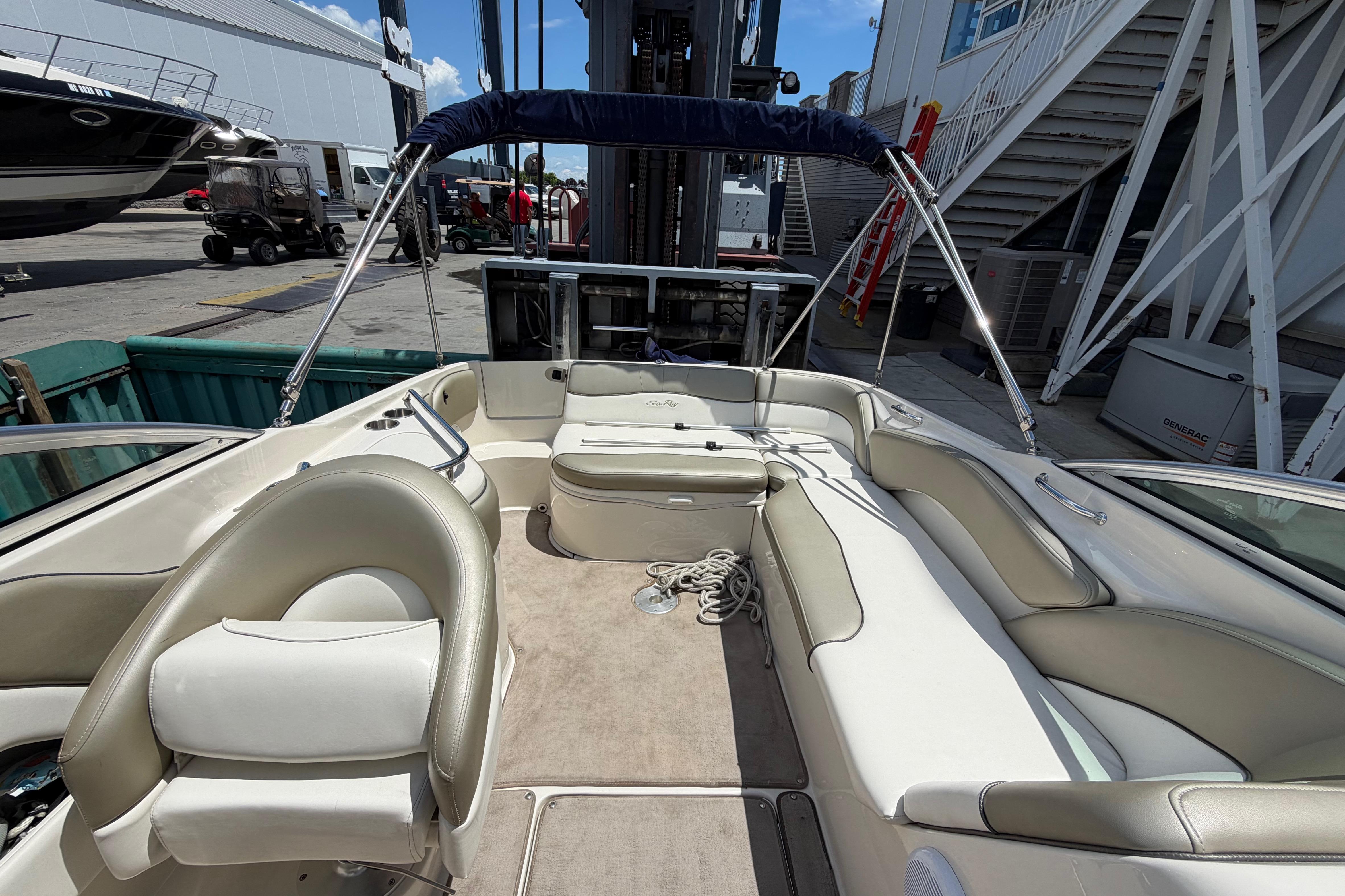 2004 Sea Ray 240 Sundeck boat interior with seating and canopy in a marina setting.