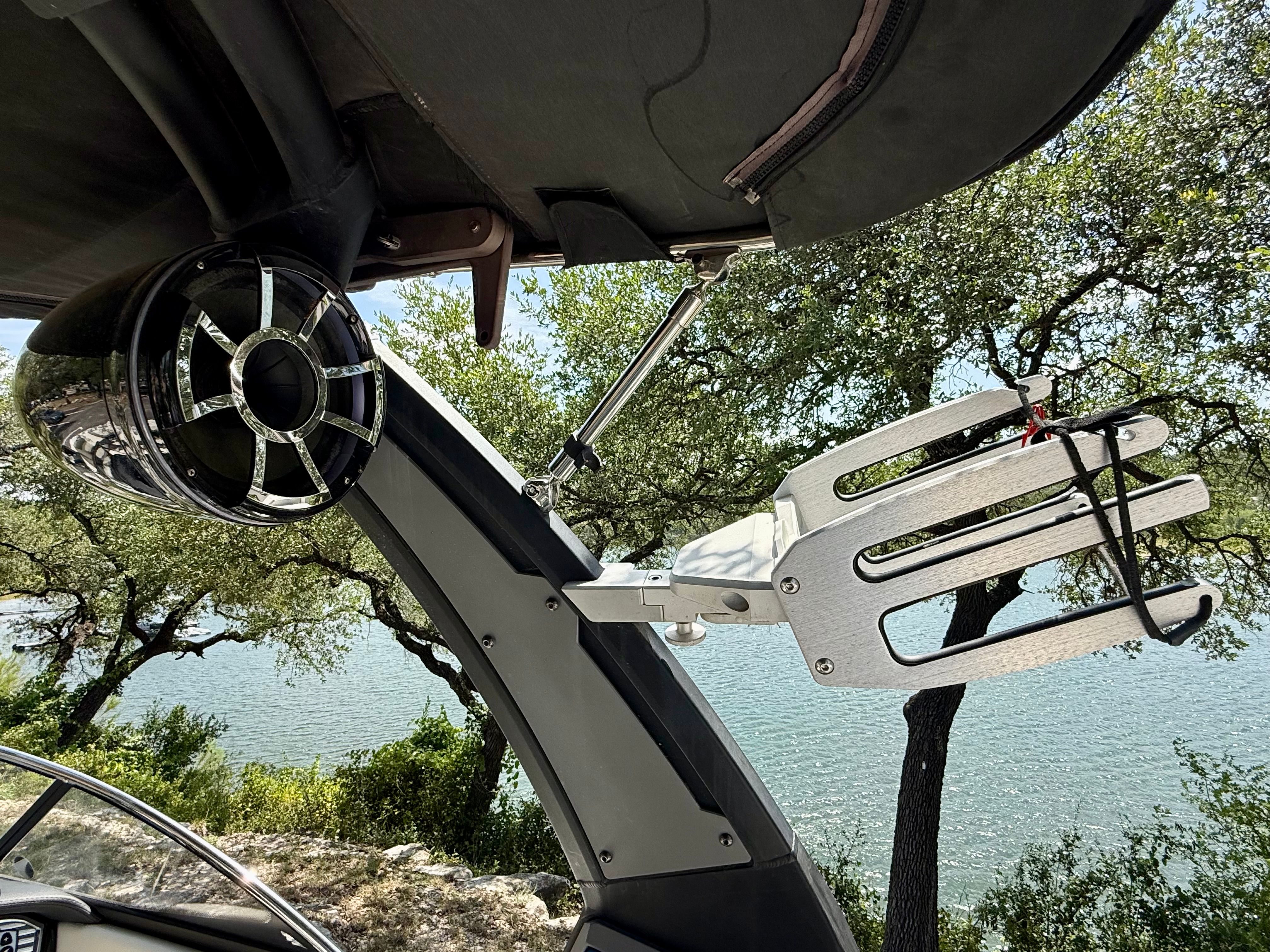 A speaker and wakeboard rack on a boat overlooking a lake.