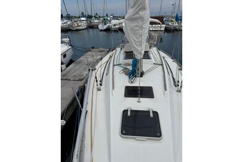 1986 Beneteau First 305 sailboat docked at marina, view of deck and mast.