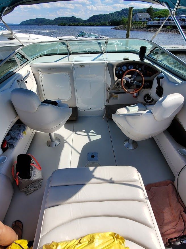 Interior of a 1998 Crownline 210 CCR boat with two white seats and a steering console.