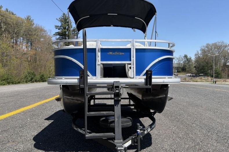2026 Sun Tracker Fishin' Barge 20 DLX pontoon boat on trailer, parked on road.