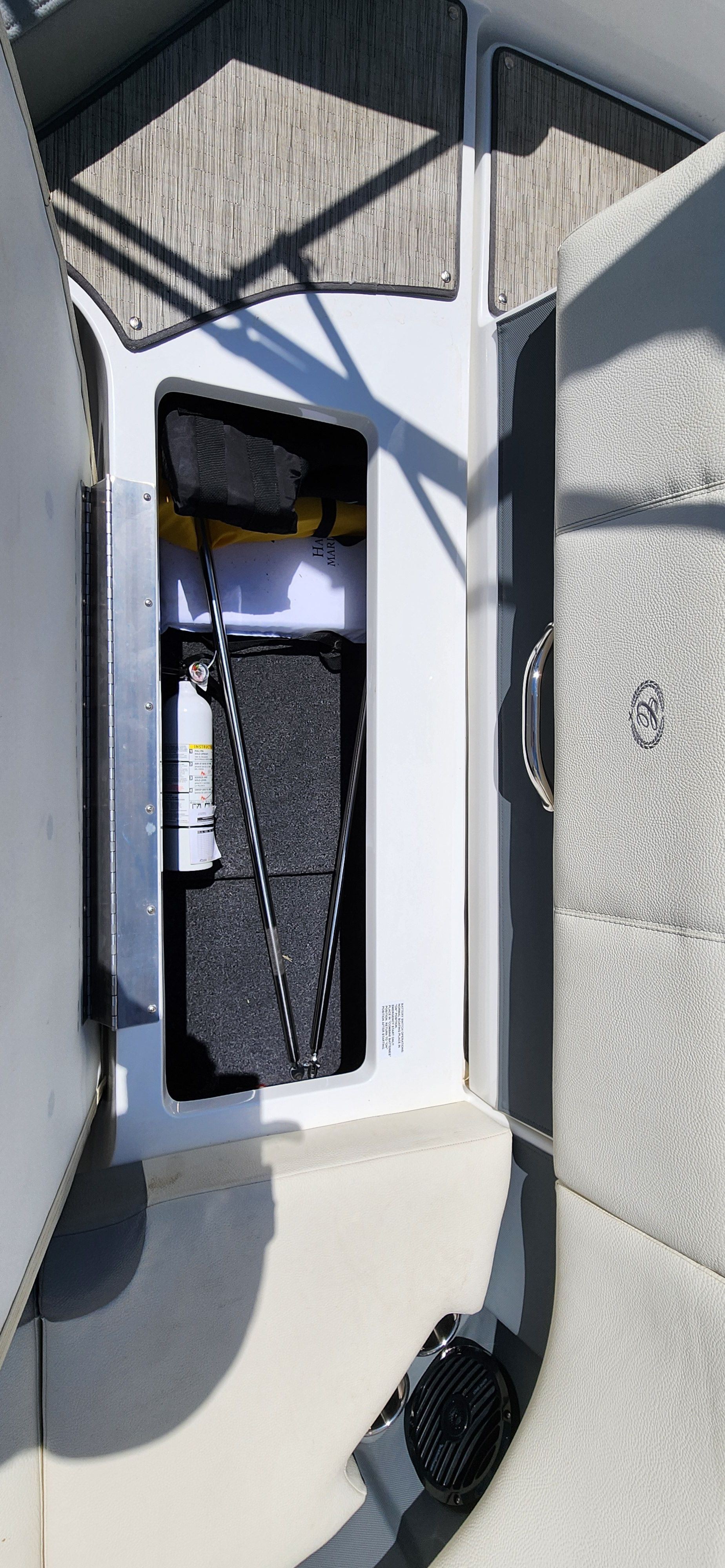An open storage compartment on a Cobalt CS22 boat with various items inside.