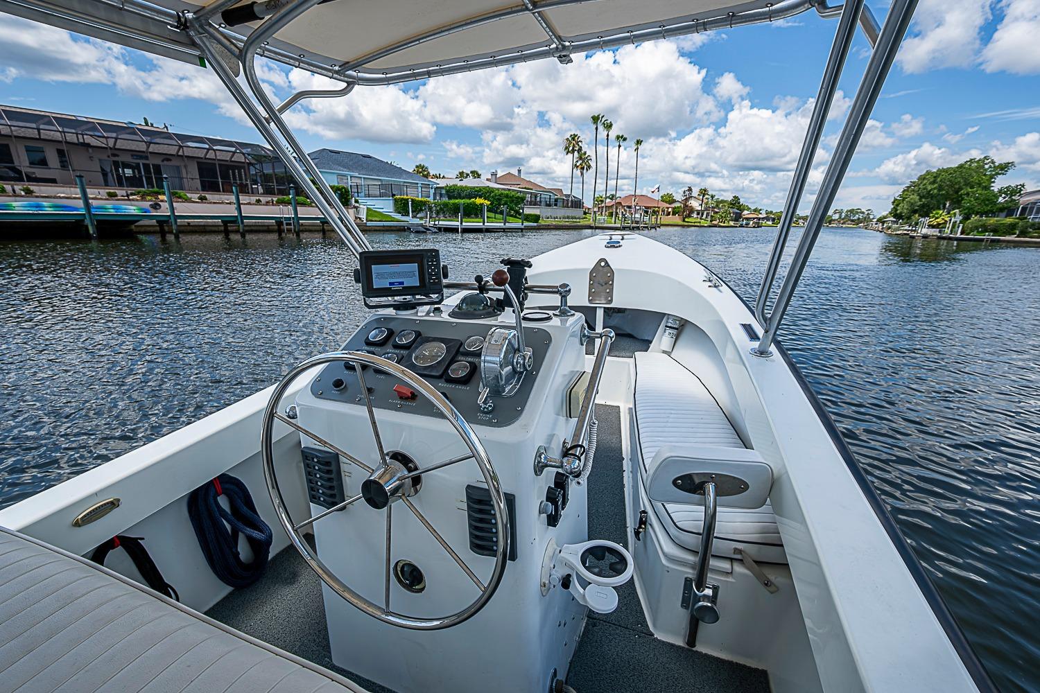 1969 custom boat interior with steering wheel, gauges, and seating on a sunny waterway.