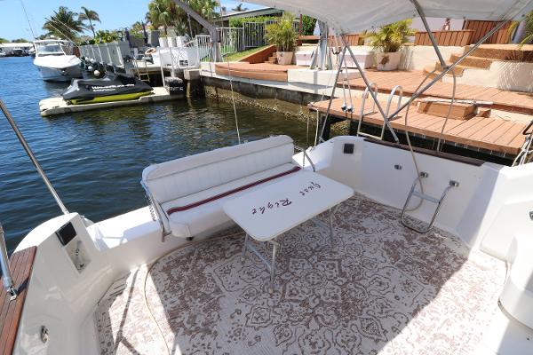 1992 Sea Ray 350 Express Bridge boat deck with seating and table, docked by the water.