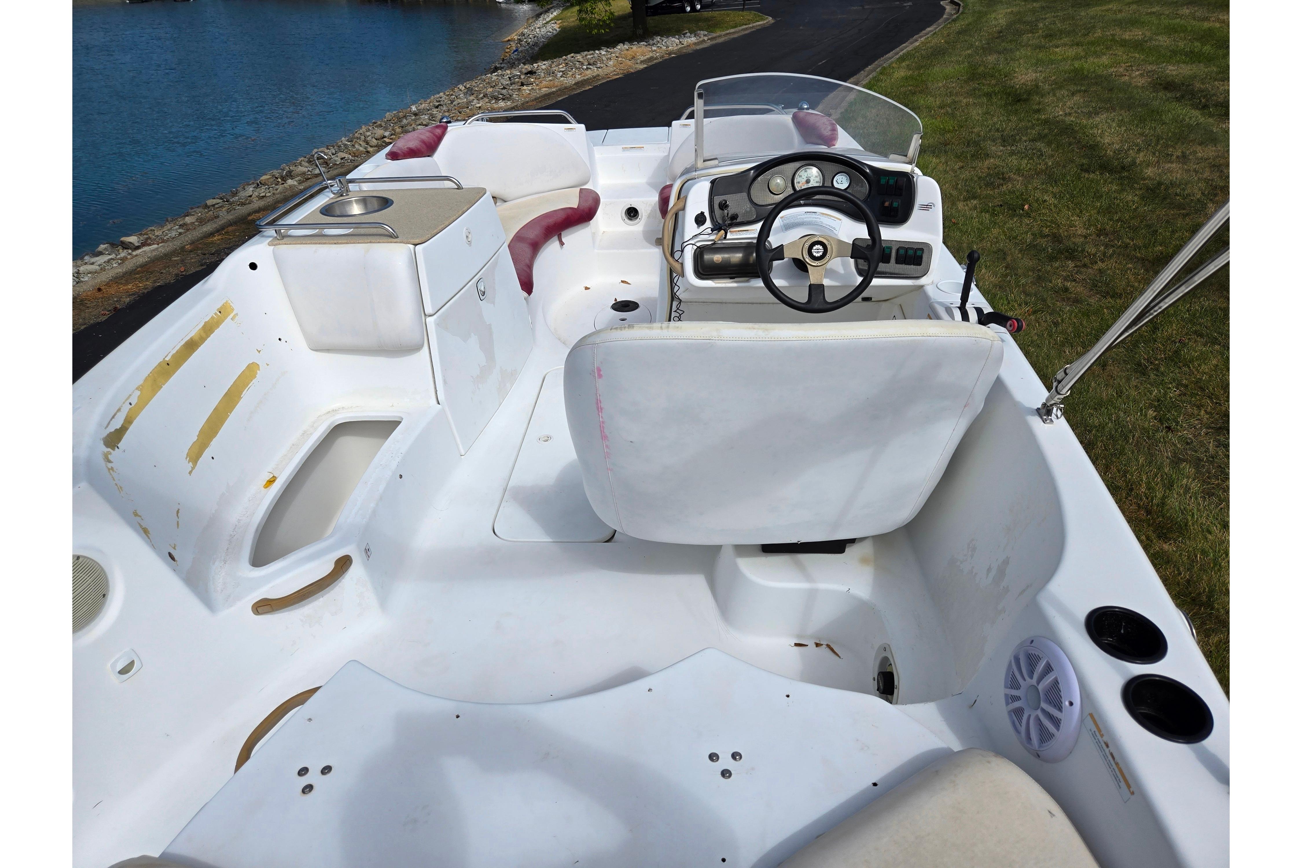 2004 Sea-Doo Islandia boat interior with steering wheel, seating, and sink by the water.
