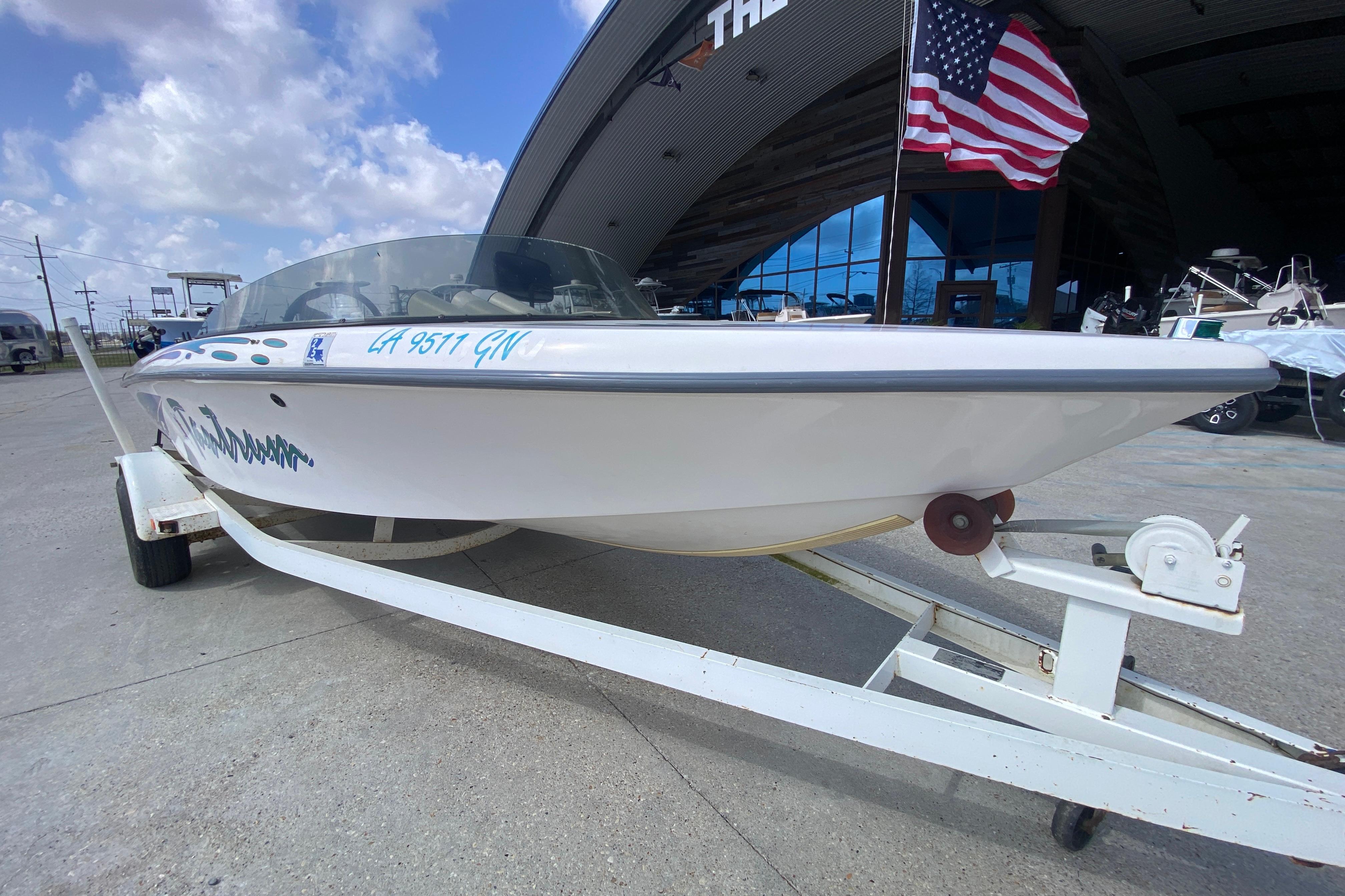 1997 Malibu Tantrum boat on trailer, parked near a building with an American flag.