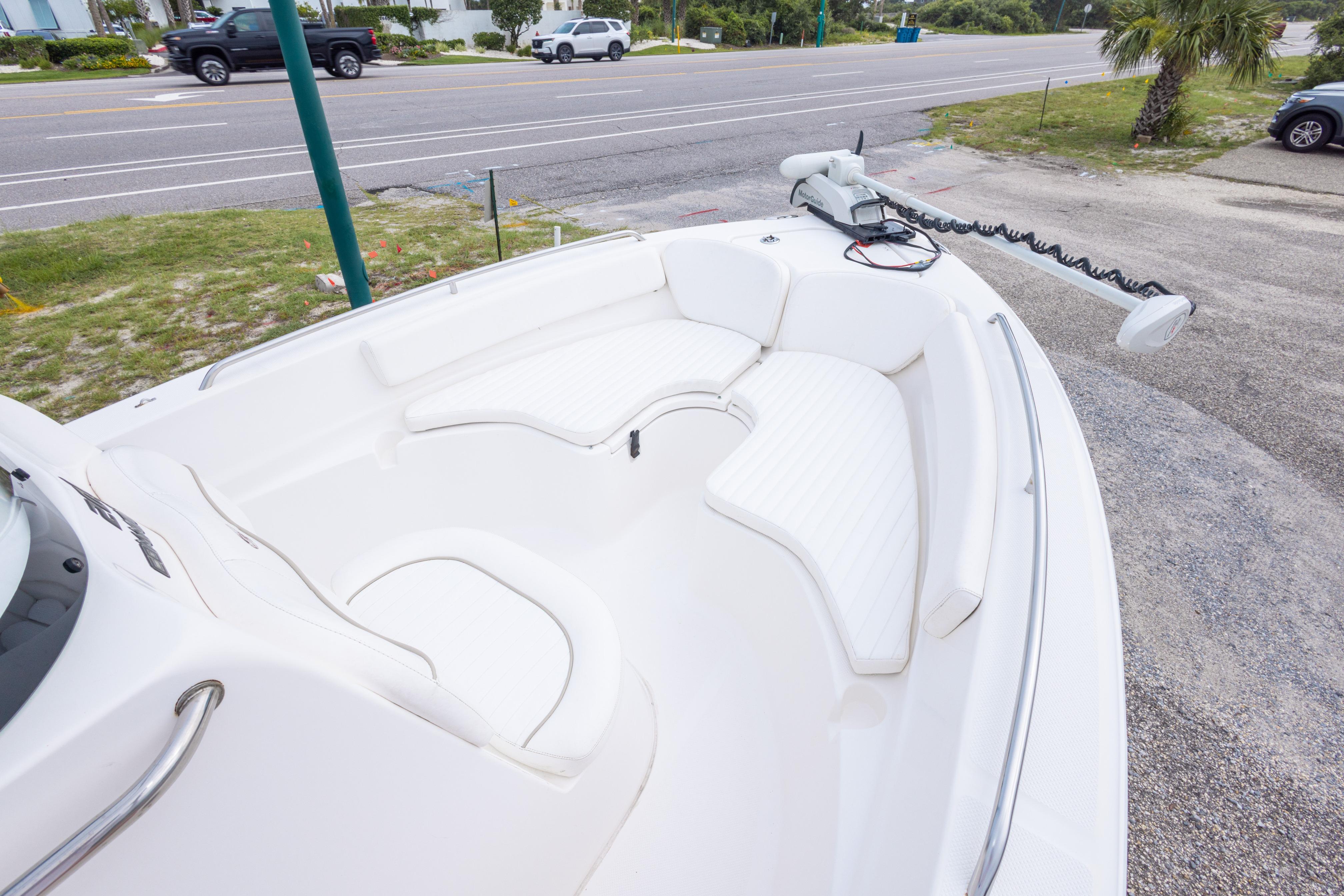 2014 Sea Fox 209 Commander boat with white seating and trolling motor, parked near a road.