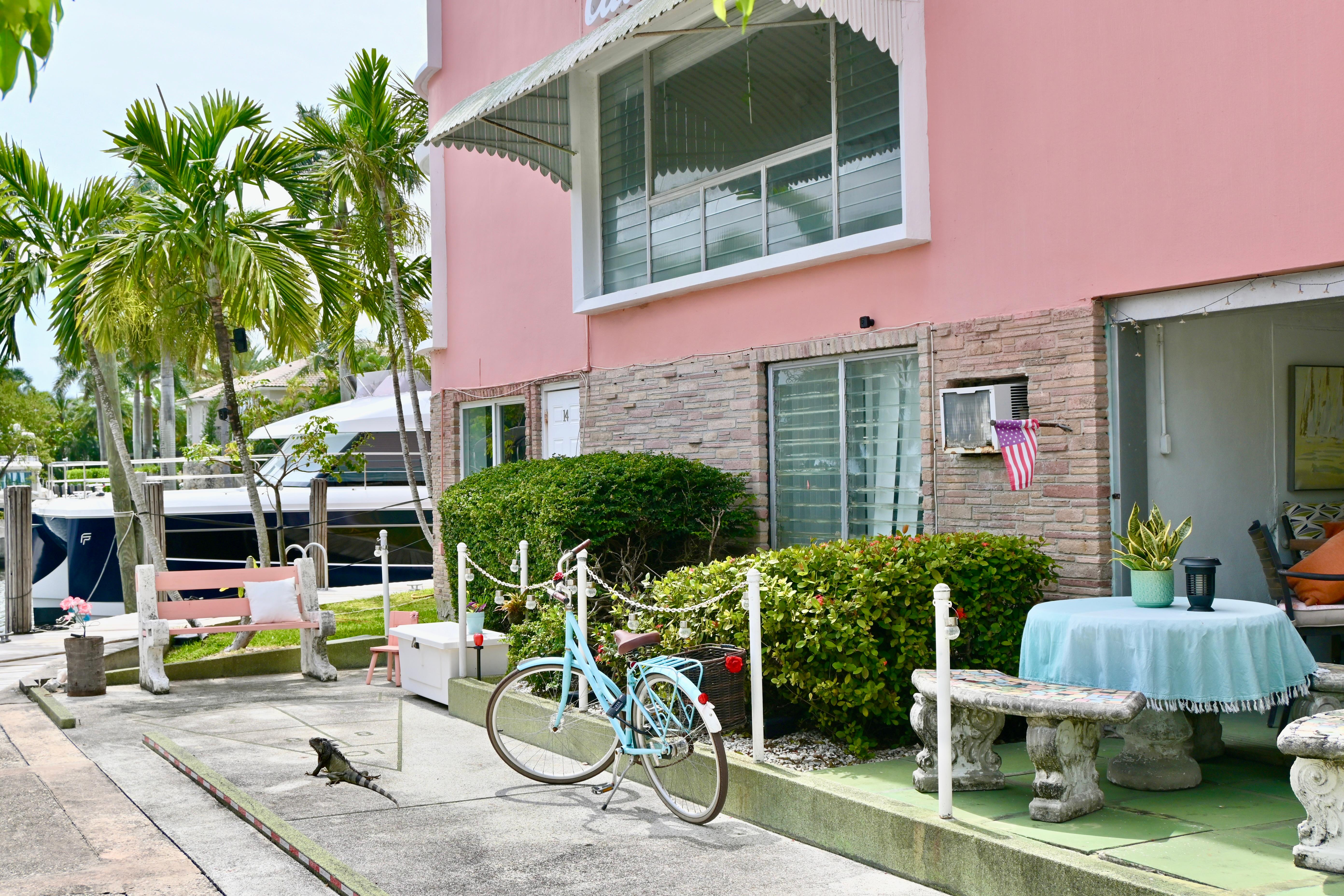 Pink building with patio, bicycle, and tropical plants near a 1979 Uniflite Double Cabin boat.