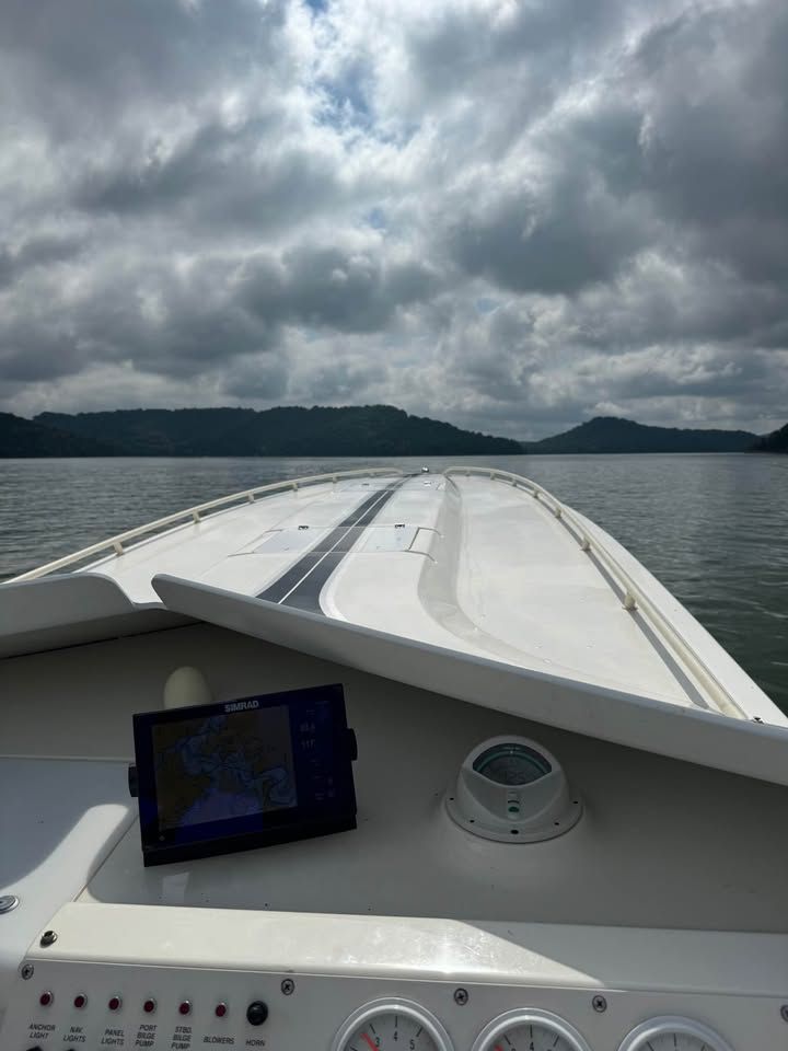 1996 Fountain 42Ft boat on calm water under cloudy sky.