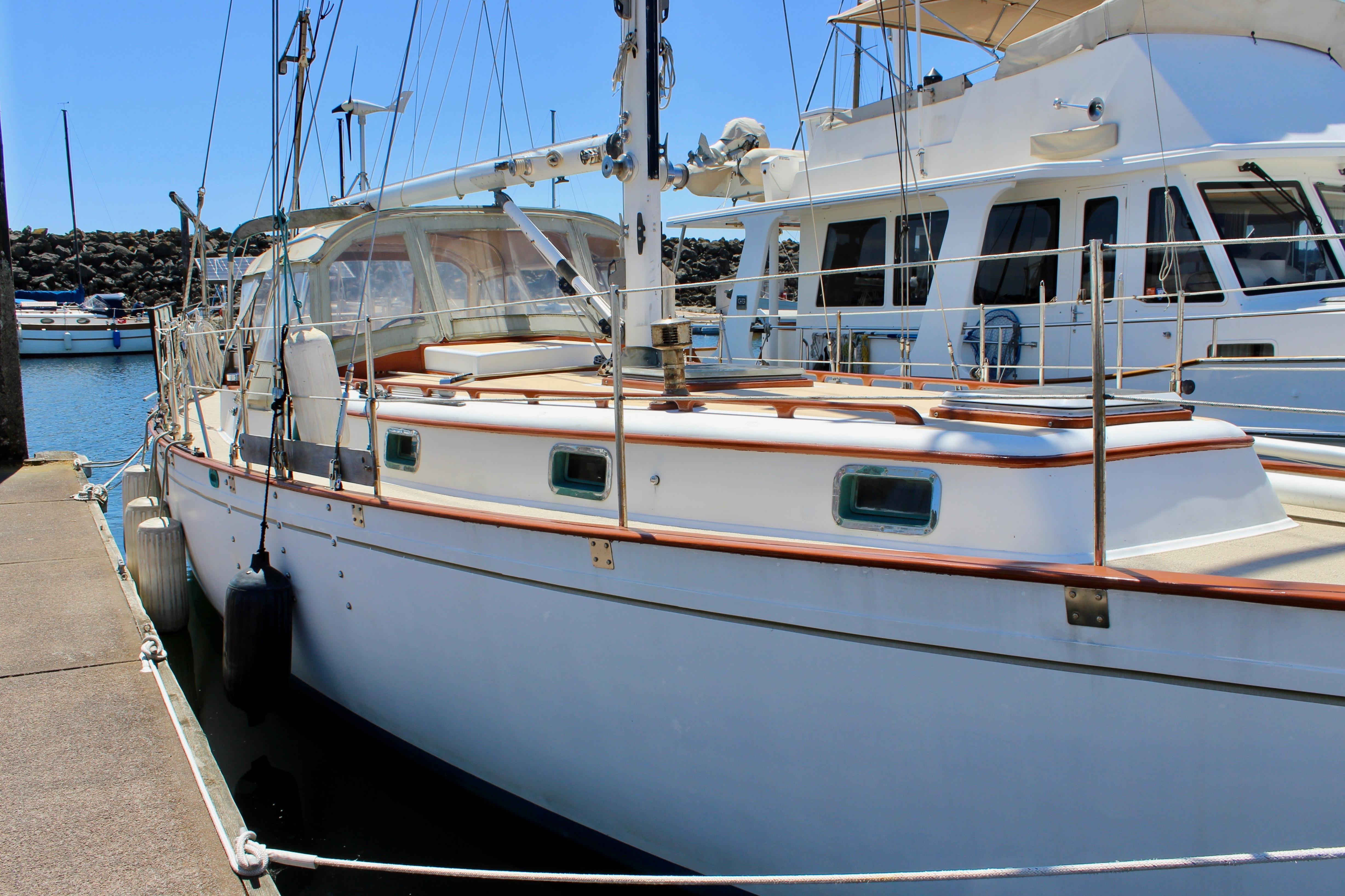 1981 Kelly Peterson 46 sailboat docked at marina under clear blue sky.