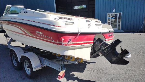 1999 Chaparral 2130 SS boat on trailer, red and white design, parked outside a building.