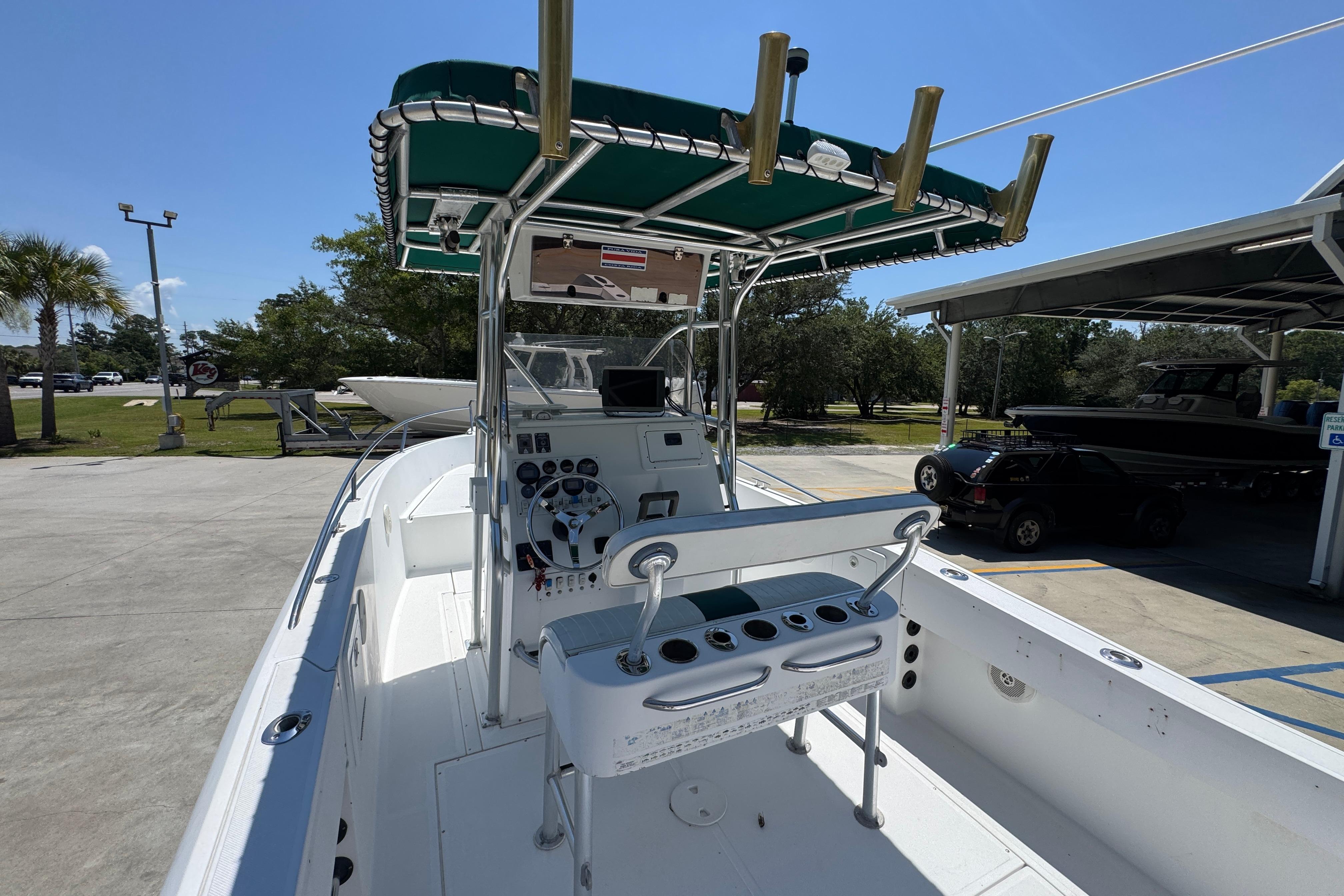 2000 Stamas 250 Tarpon boat with green canopy, docked outdoors on a sunny day.