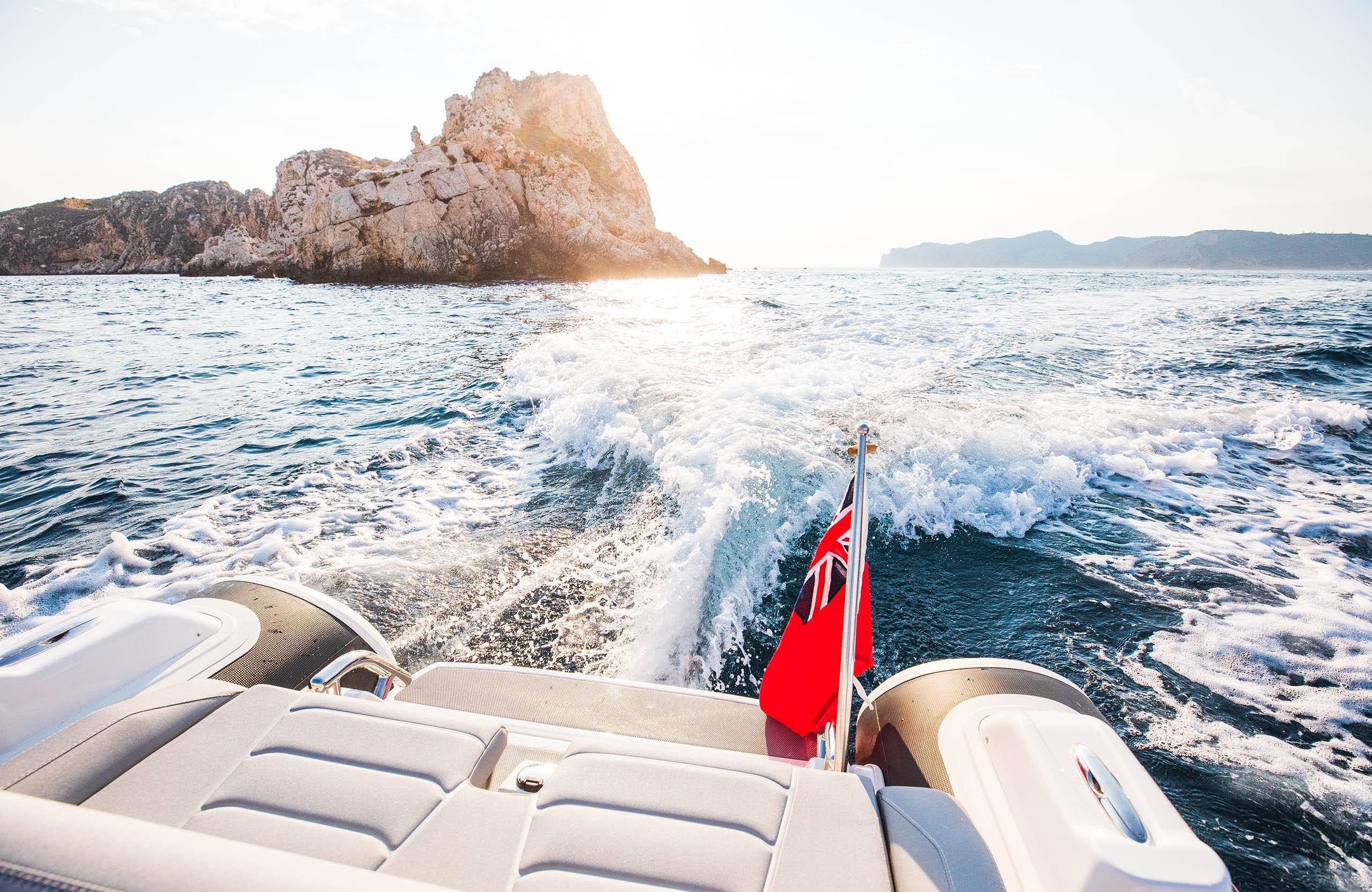 2025 Williams Jet Tenders Sportjet 435 cruising near rocky island, ocean waves trailing behind.