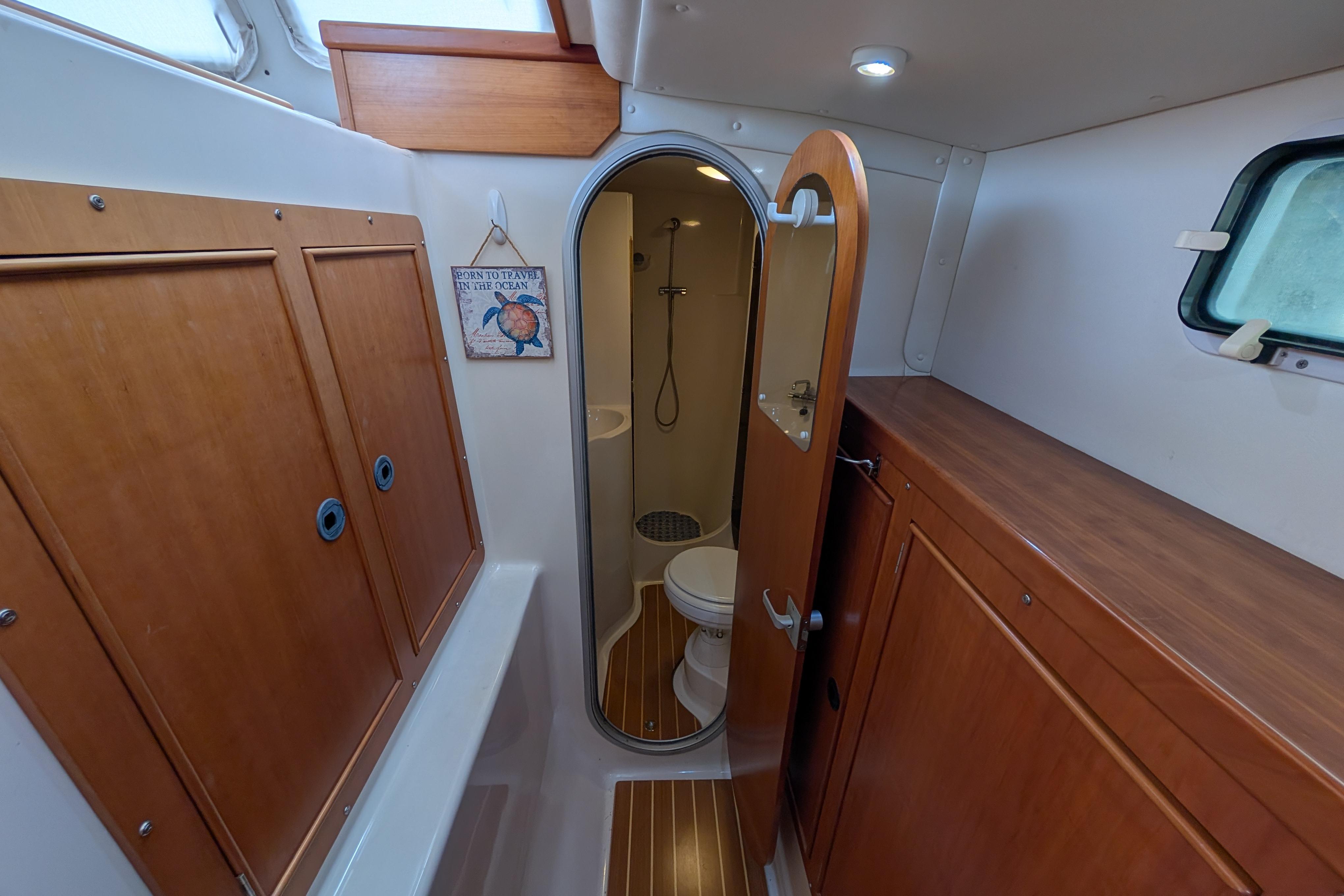 2004 PDQ 34 Powercat interior bathroom with wooden cabinets and nautical decor.