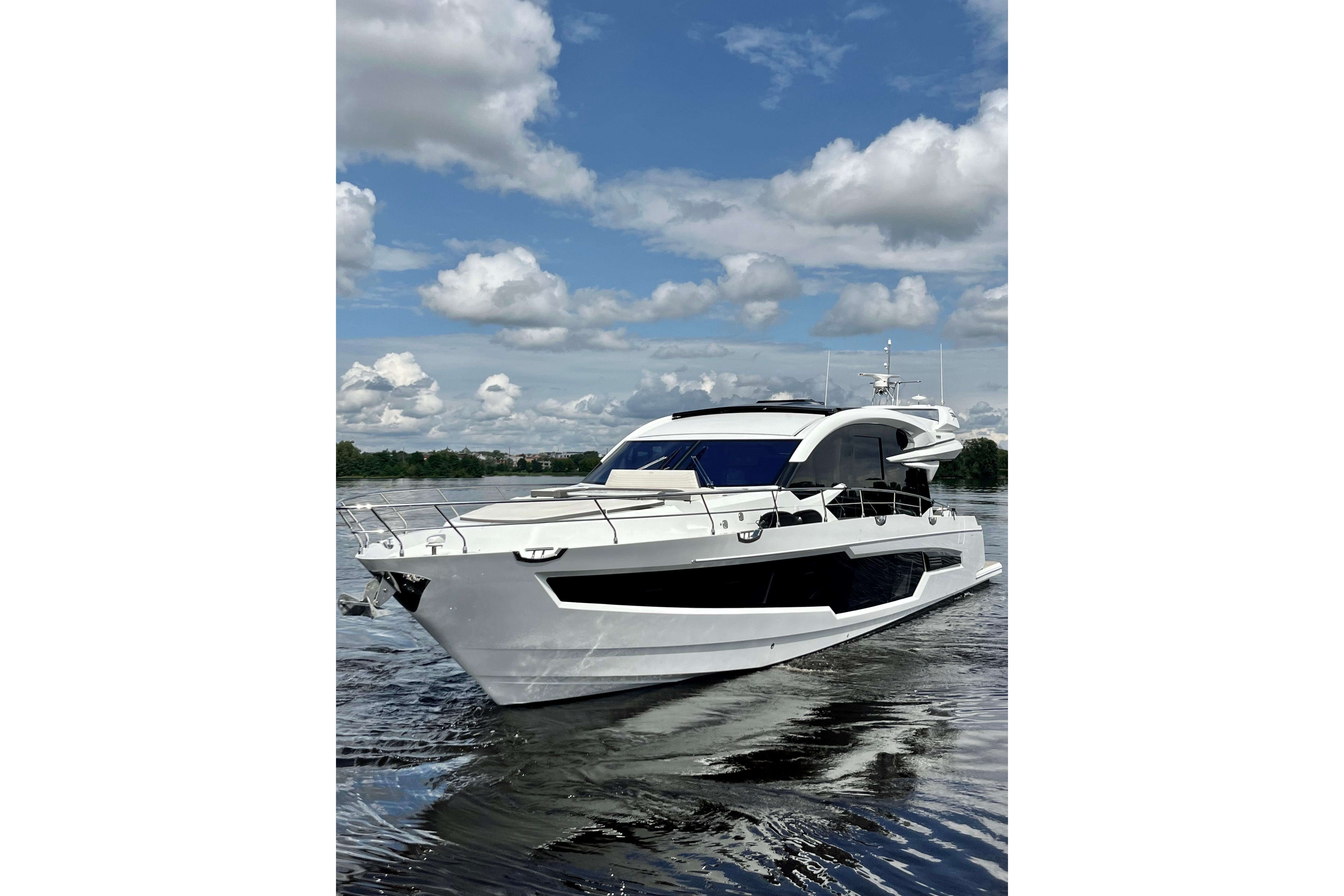 2025 Galeon 700 Sky yacht cruising on a calm waterway under a partly cloudy sky.
