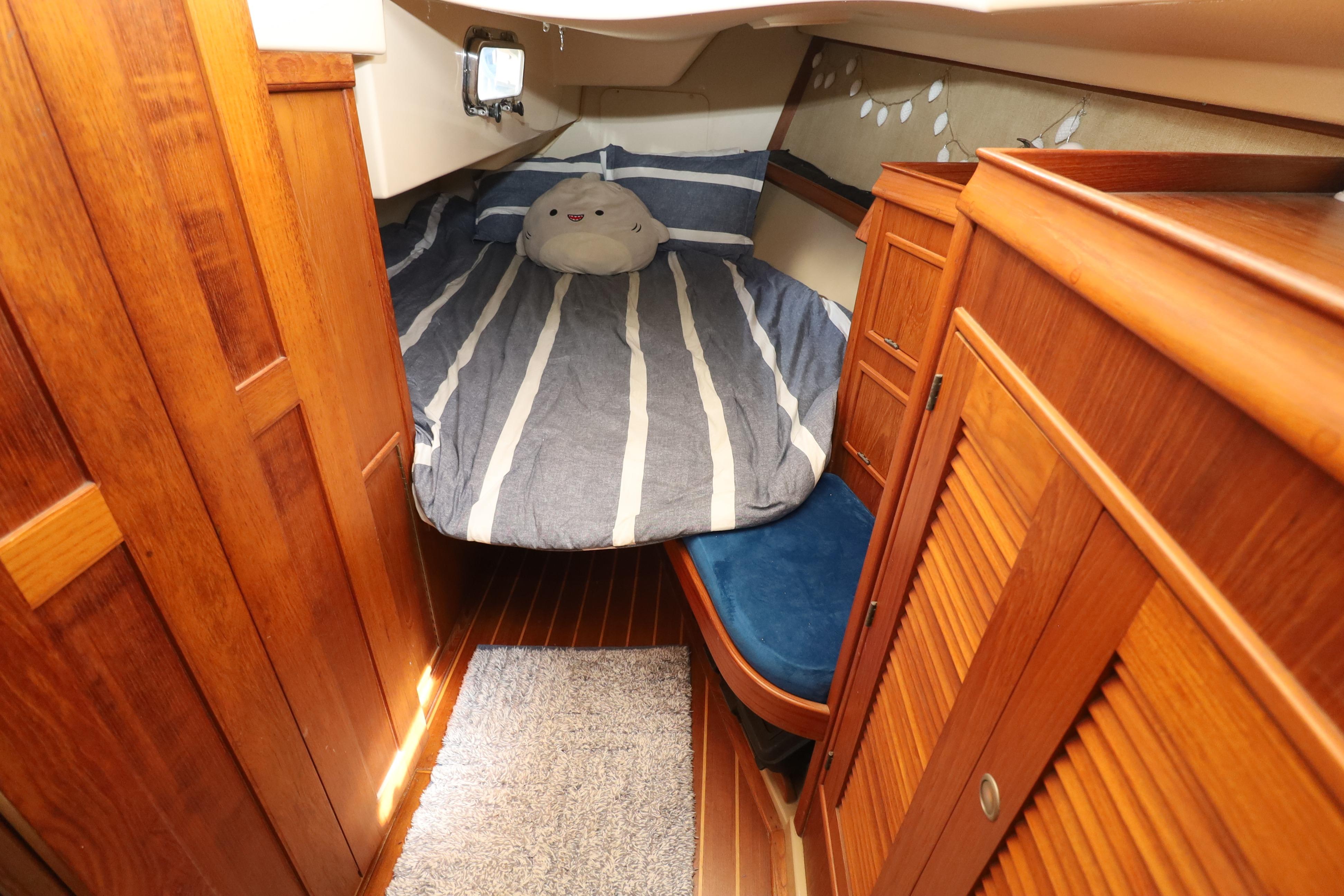 Cozy cabin interior of 1996 Island Packet 40 sailboat with striped bedding and wooden furnishings.