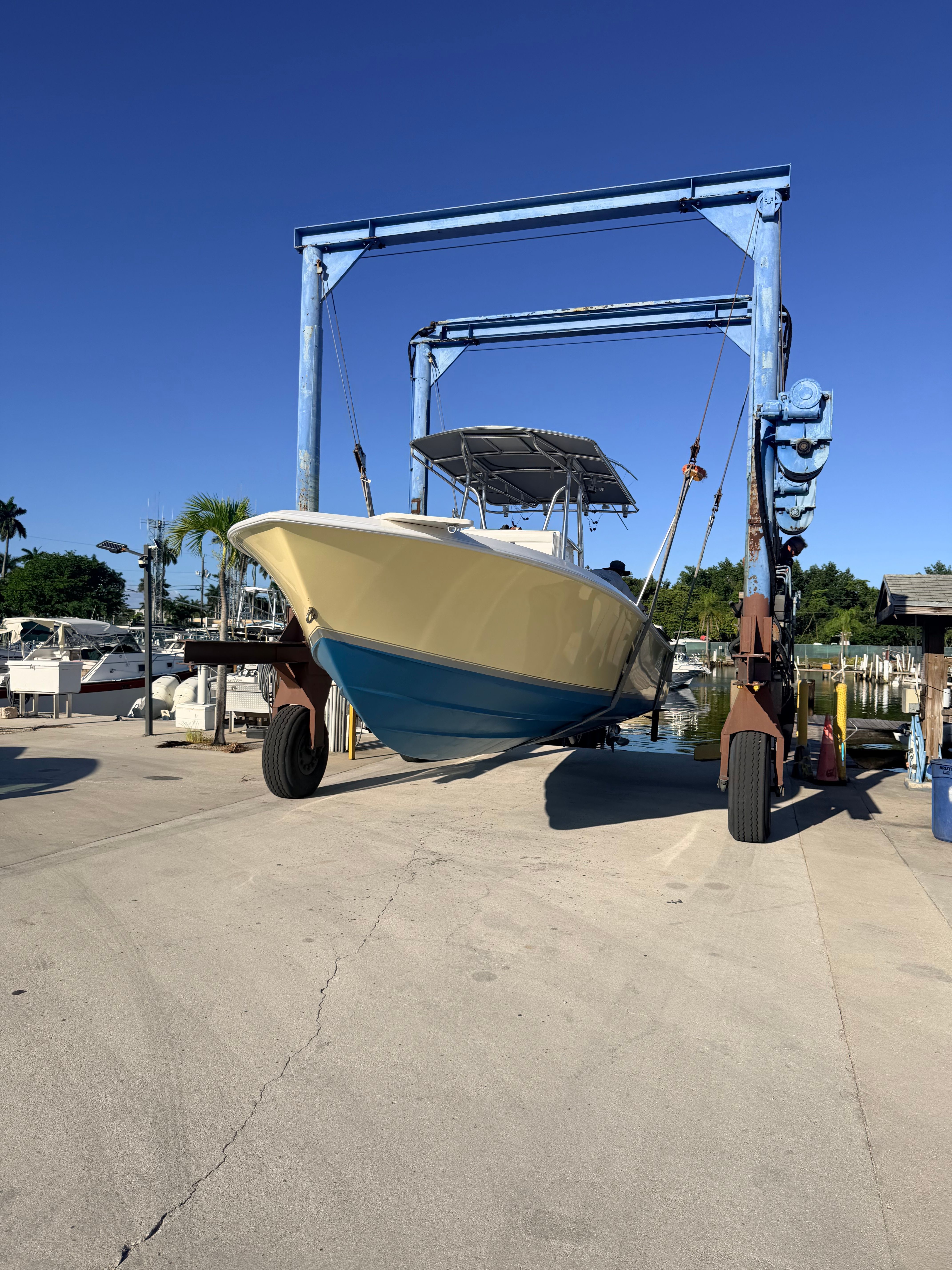 A yellow boat is being lifted out of the water by a crane.