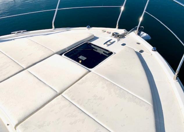 2016 Carver C37 yacht bow with sunpad and hatch, on calm water.