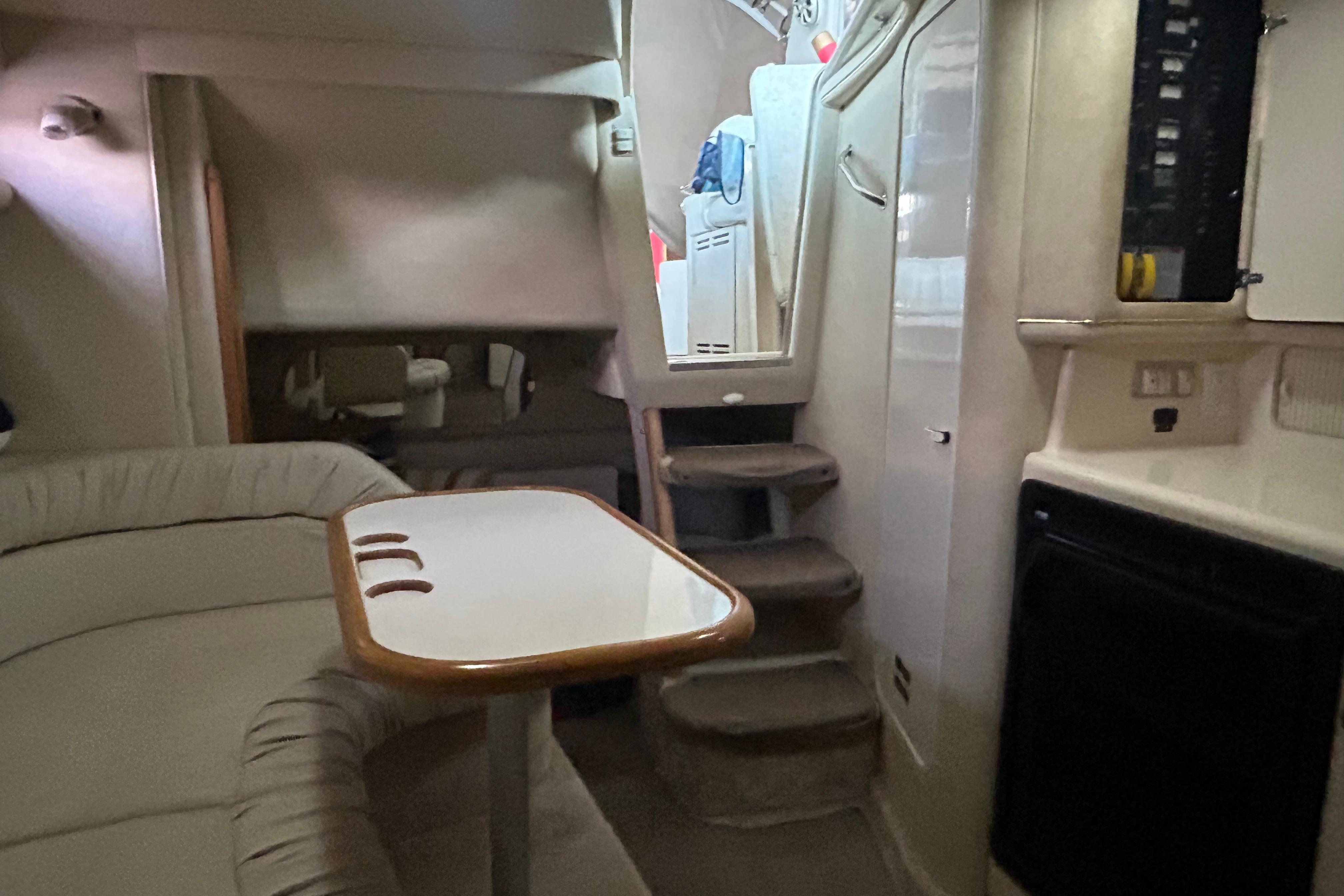 Interior of a 1997 Sea Ray Sundancer 330 yacht, featuring a cozy seating area and compact kitchen.