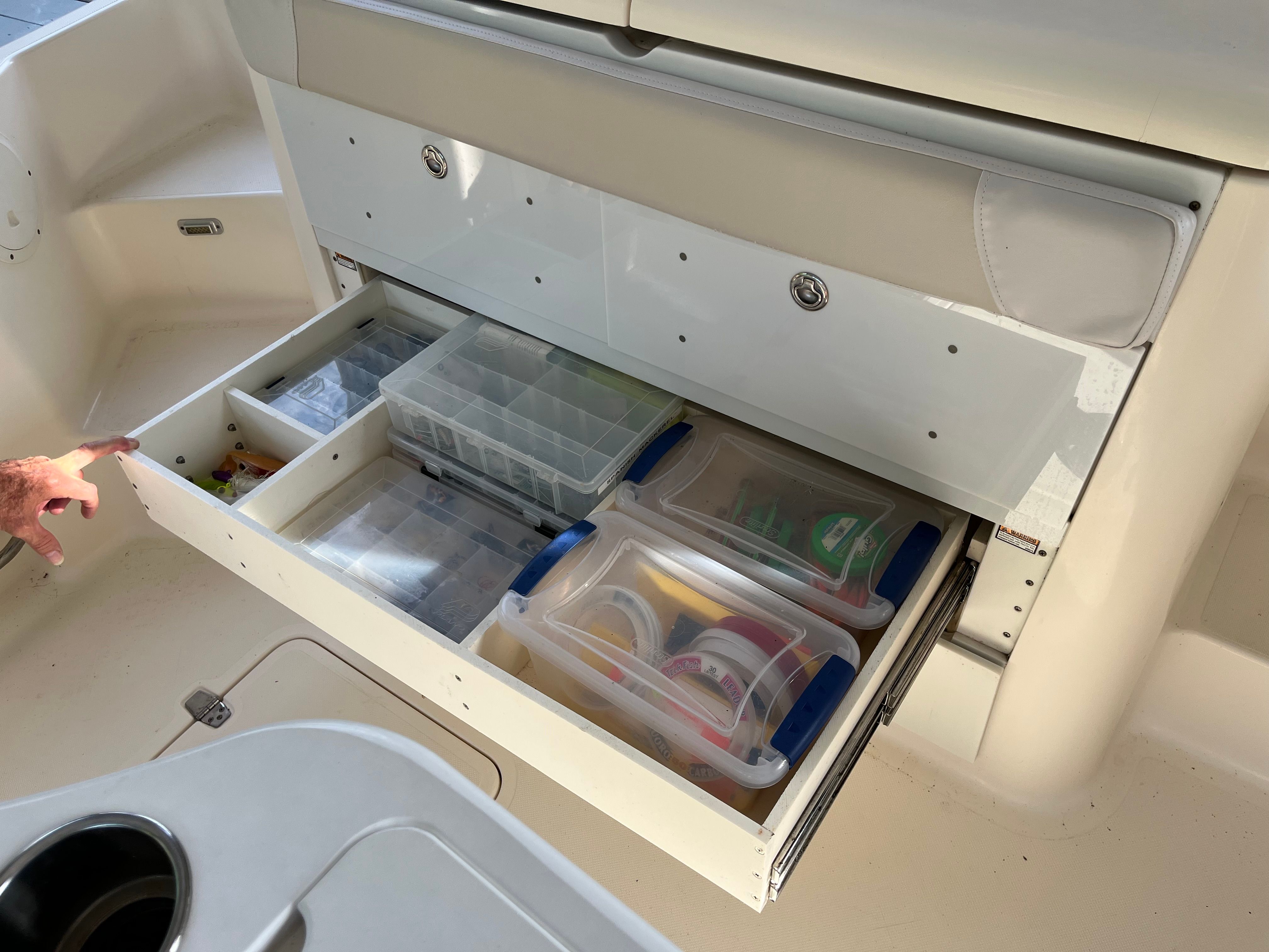 2010 Pursuit OS 345 Offshore boat storage drawer with organized fishing gear and tackle boxes.