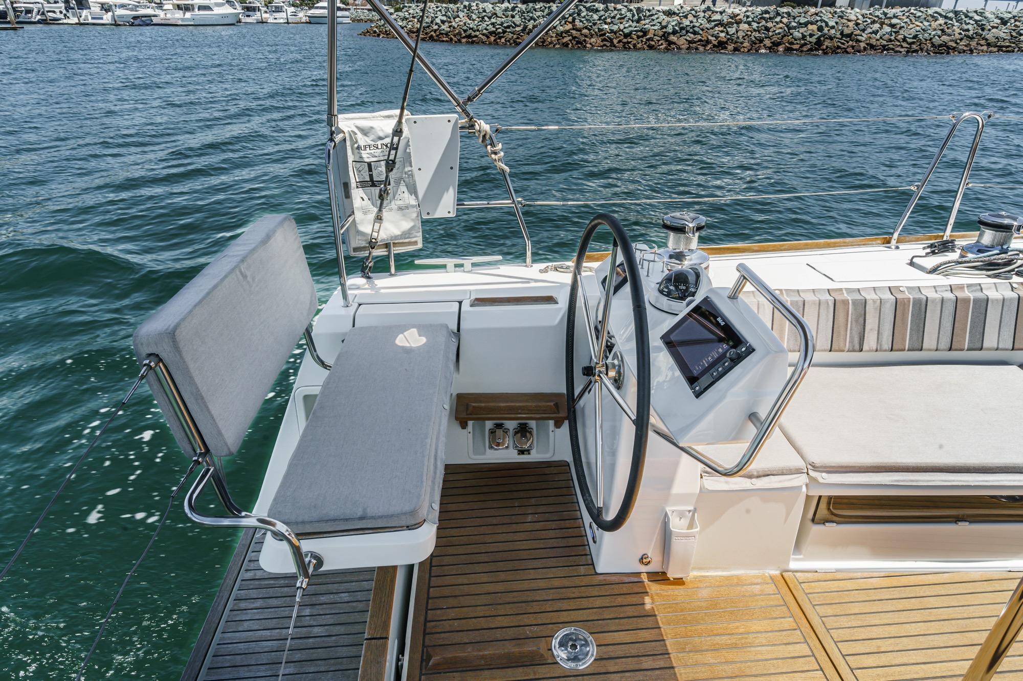 Cockpit of 2017 Beneteau Sense 50 yacht with steering wheel and seating, docked at marina.